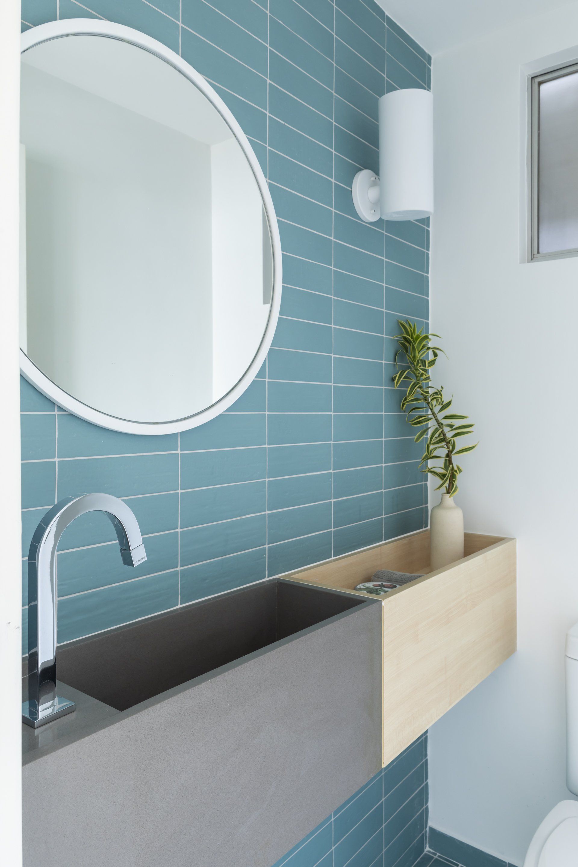 Uma casa de banho com azulejos azuis, um lavatório, um espelho e uma sanita.