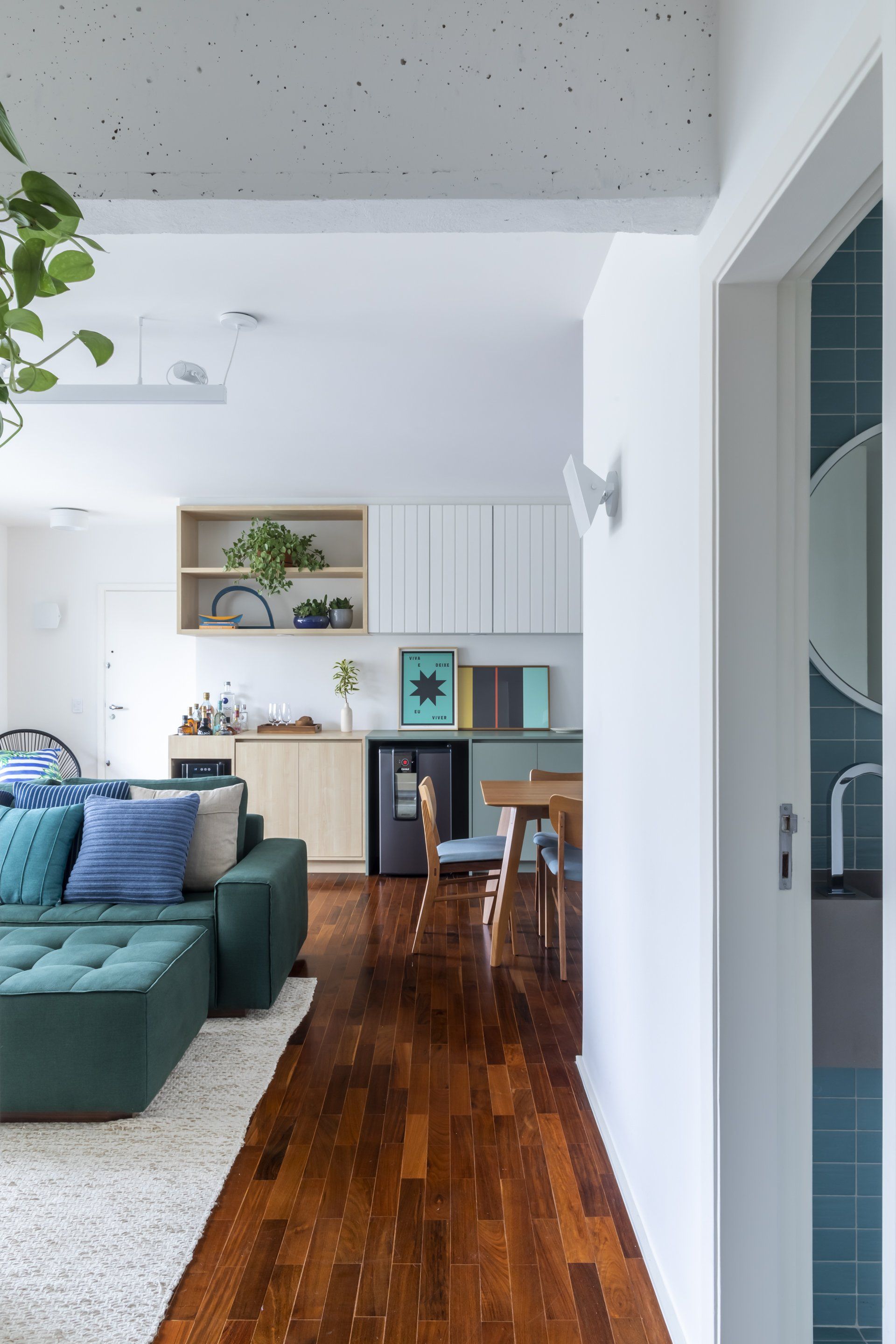 Uma sala com sofá verde e piso de madeira.