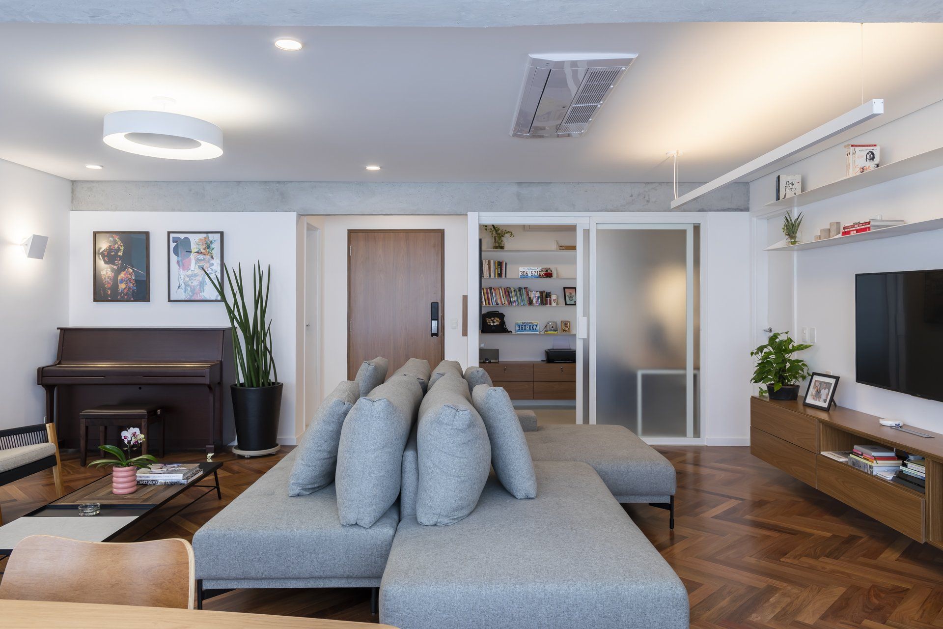 Uma sala de estar com sofá, piano e televisão