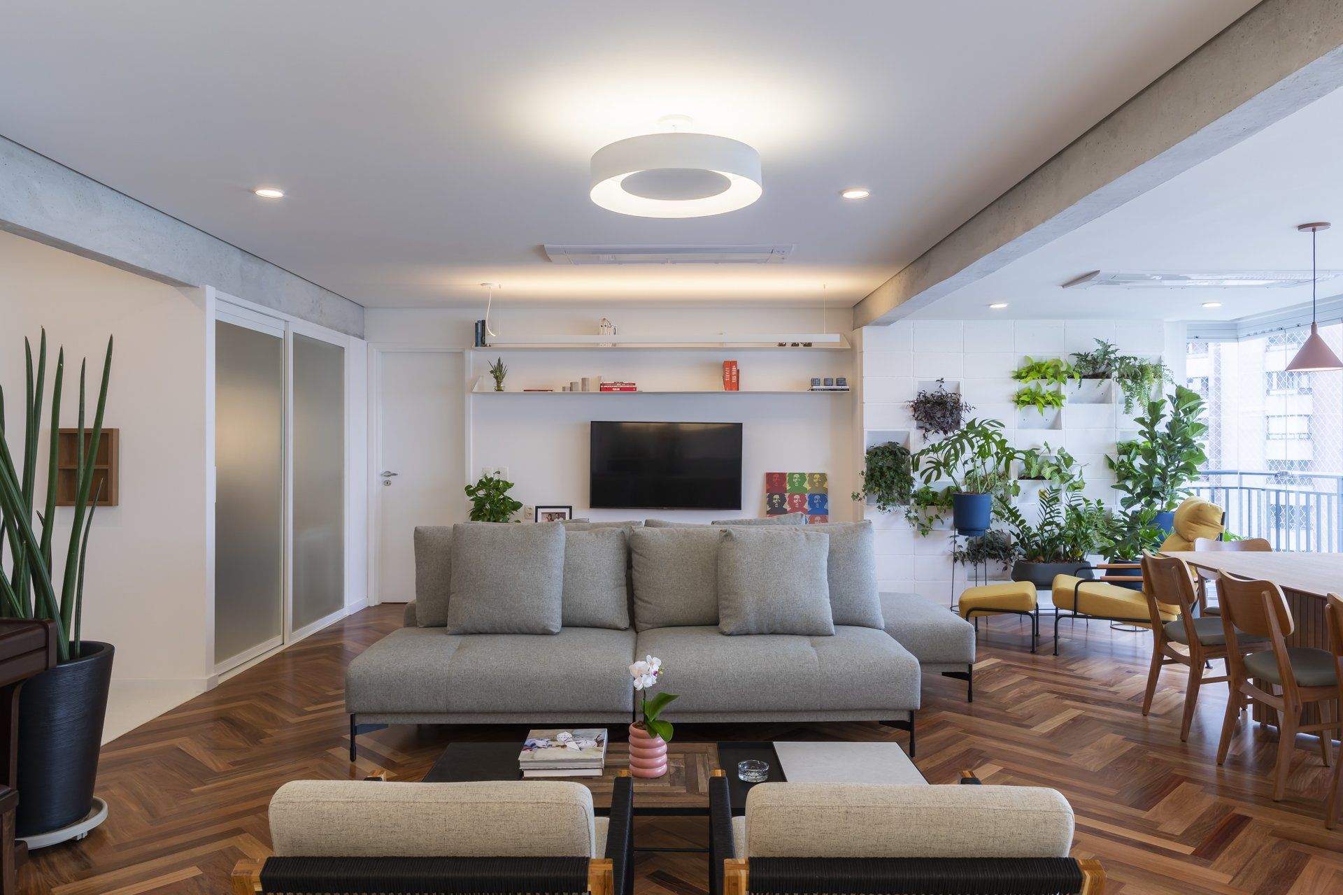 Uma sala de estar com sofá, cadeiras e TV de tela plana.