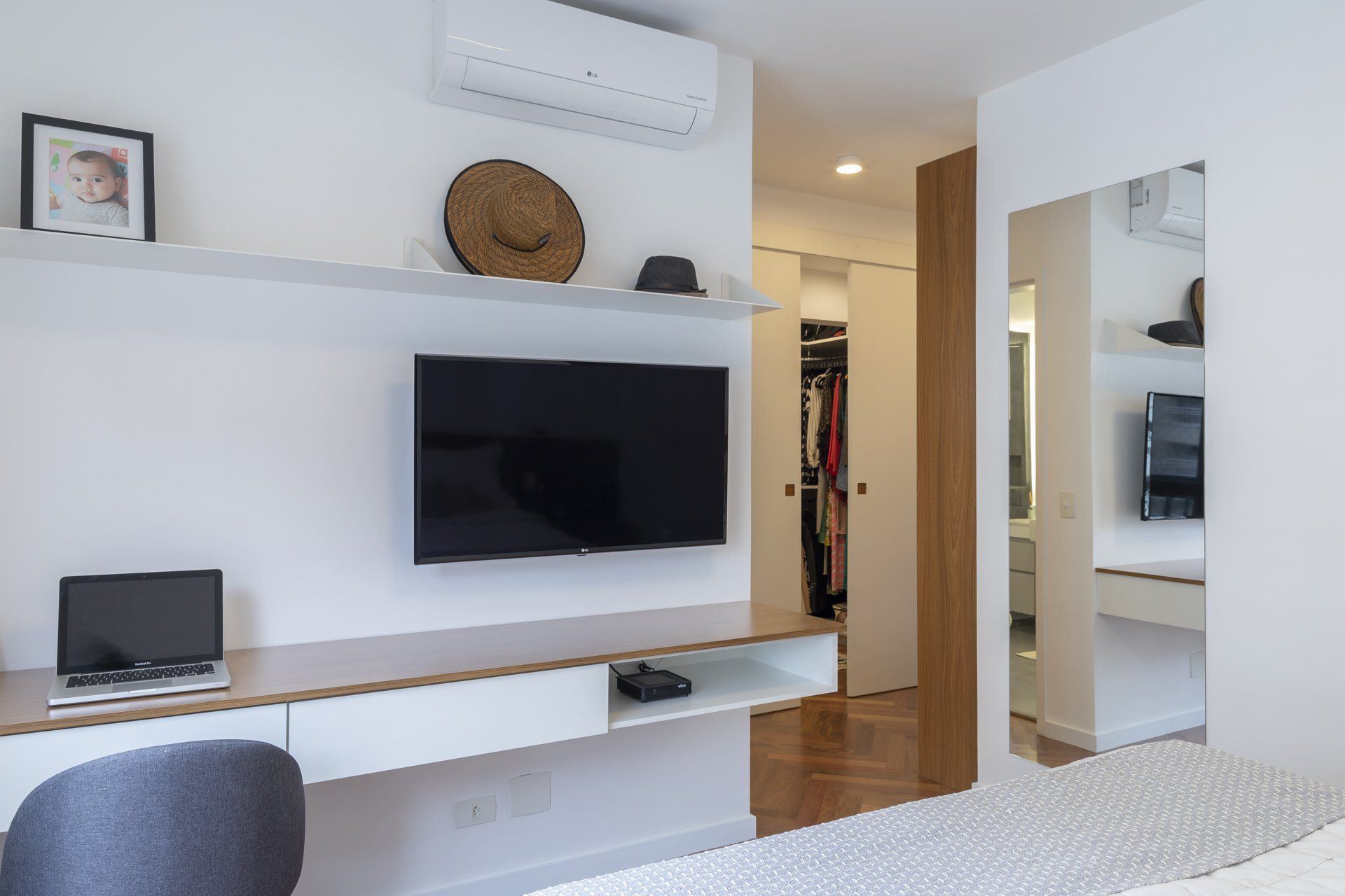 Um quarto com mesa e TV de tela plana na parede.