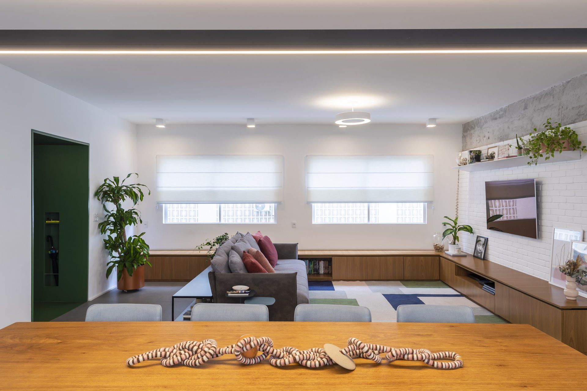 Uma sala com sofá, mesa, cadeiras e televisão.