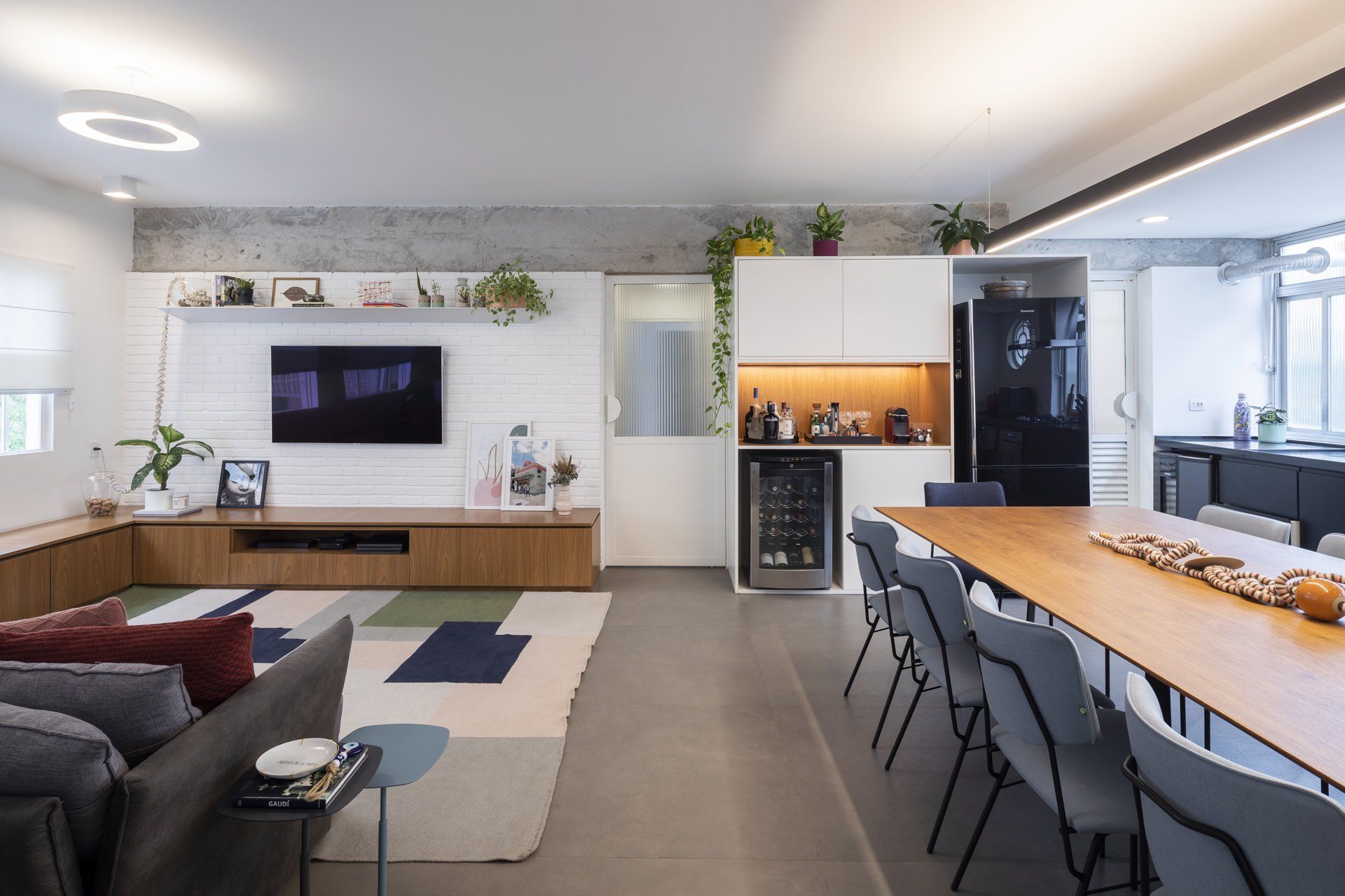 Uma sala com sofá, mesa, cadeiras e televisão.