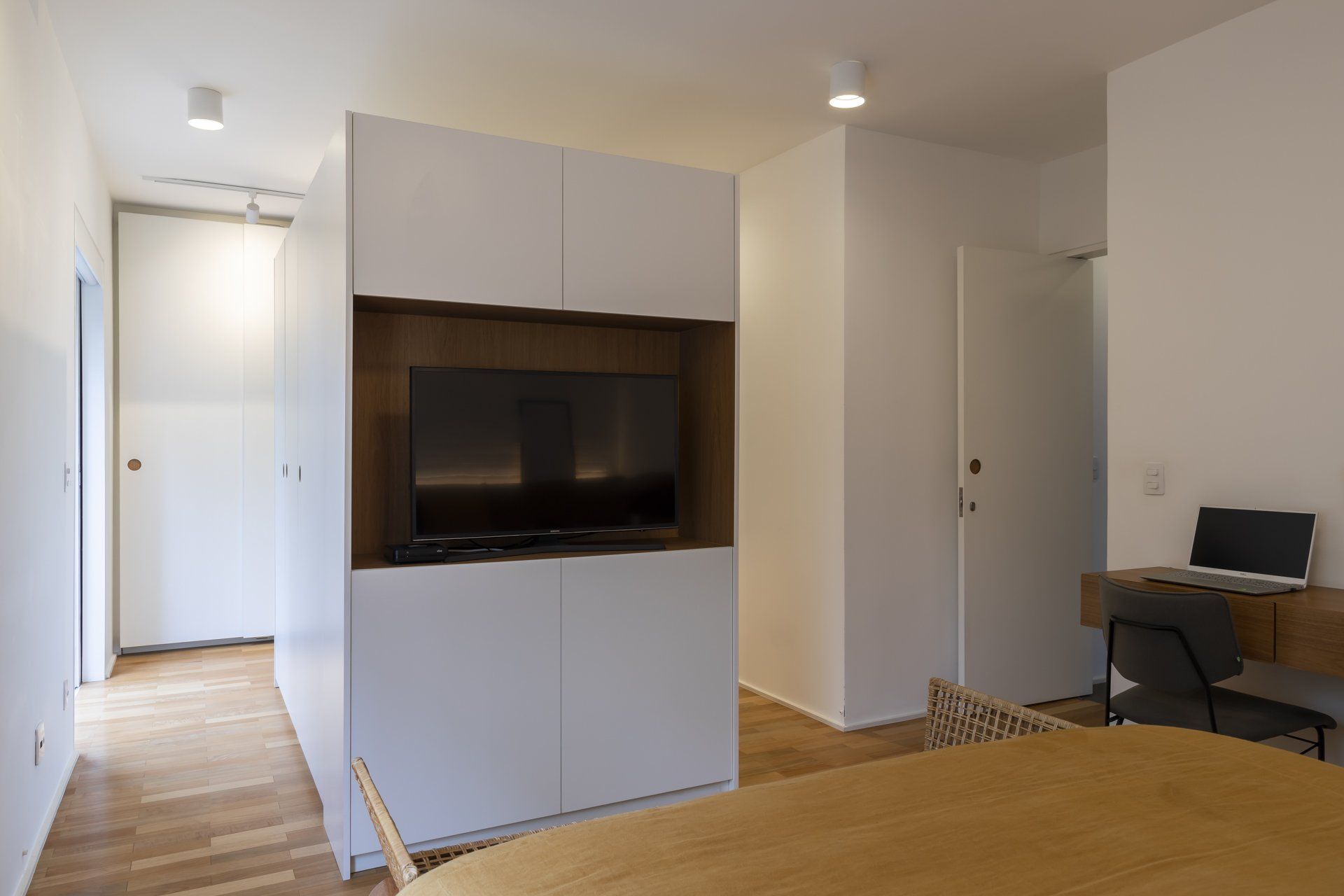 Uma sala de estar com mesa, cadeiras e televisão.