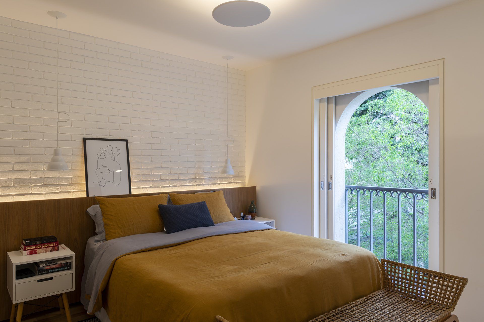 Um quarto com cama, mesa de cabeceira e varanda.