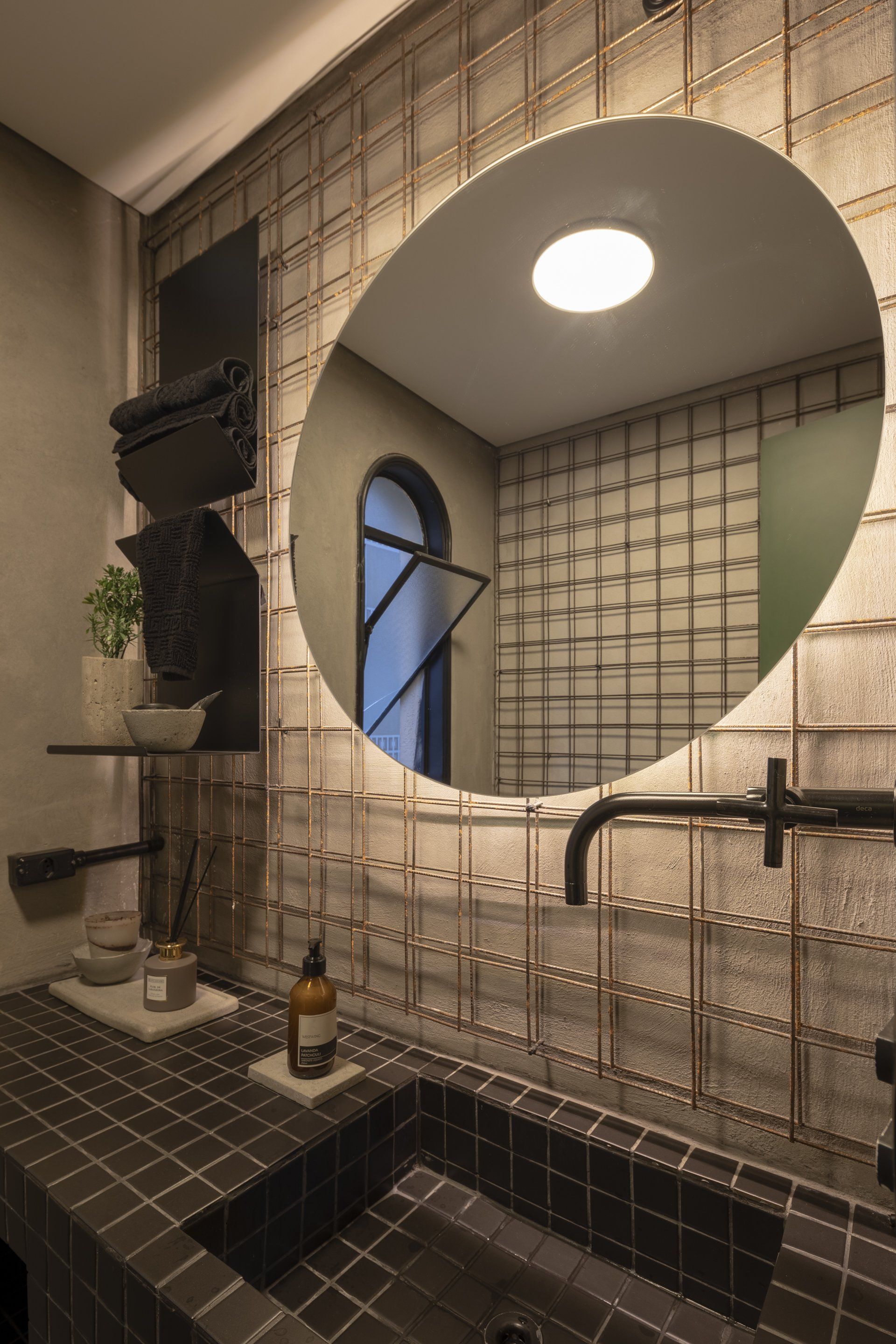 Um banheiro com pia e espelho redondo.