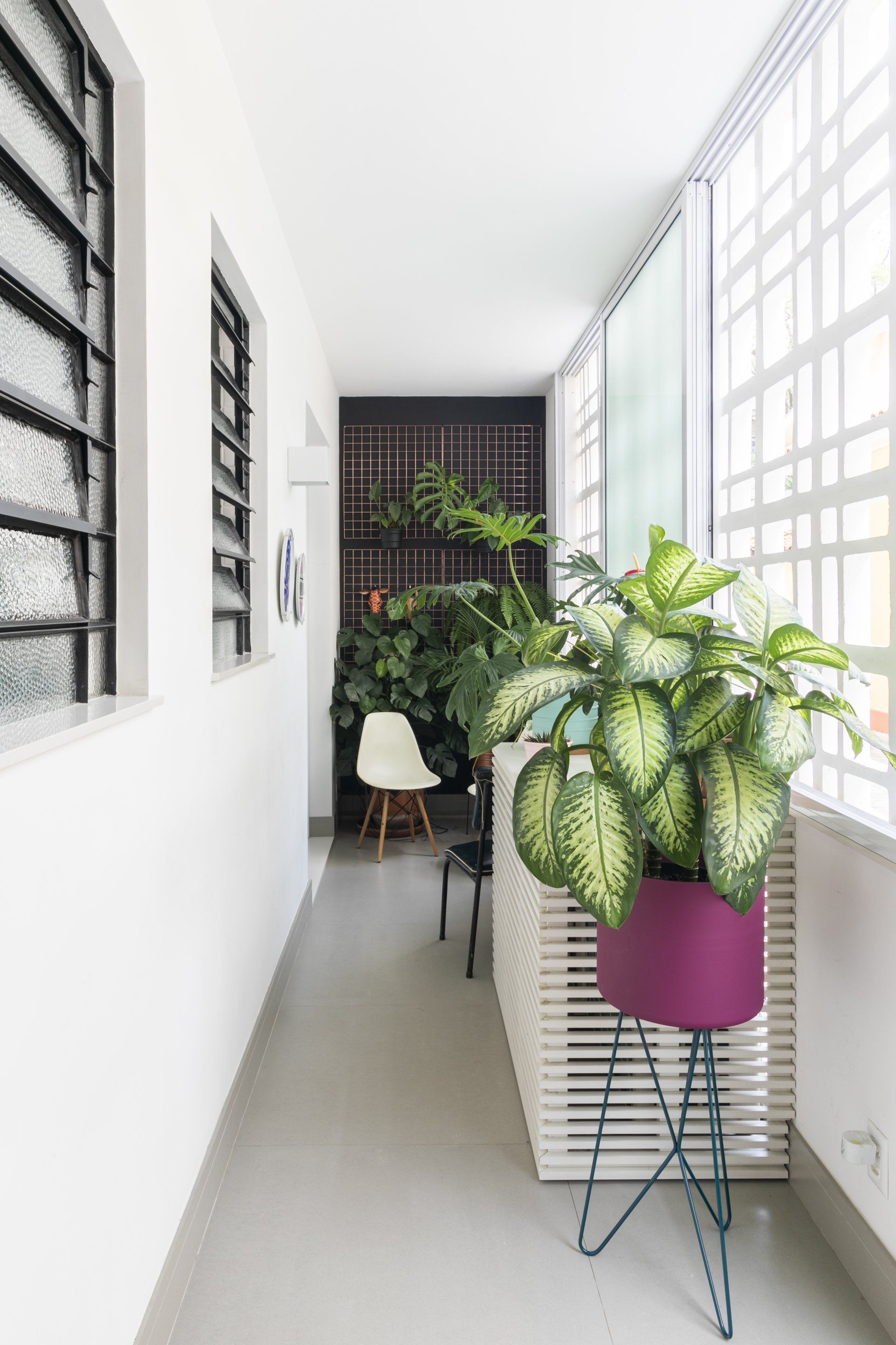 Um longo corredor com um vaso de planta no meio.