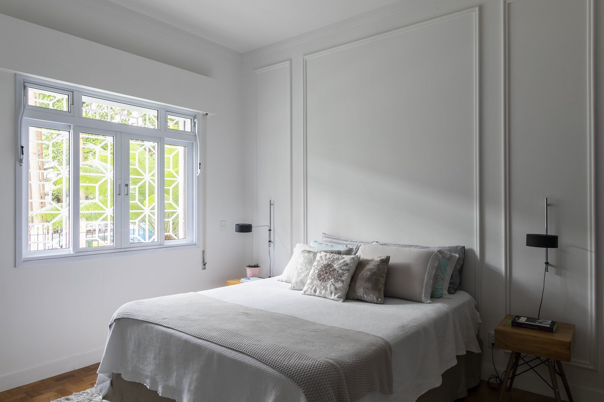 Um quarto com cama, mesa de cabeceira e janela.