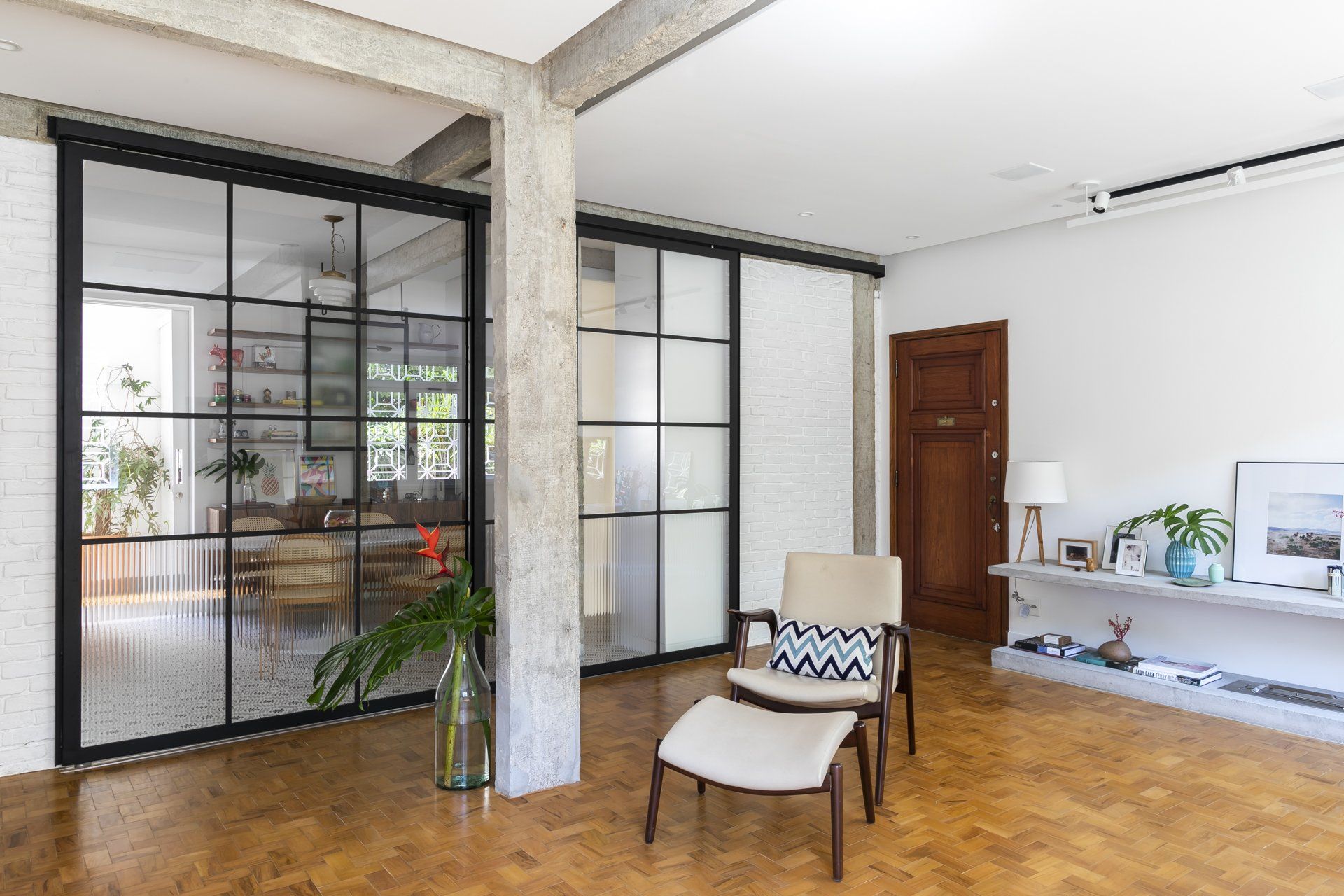 Uma sala de estar com cadeira, pufe e portas de correr de vidro.