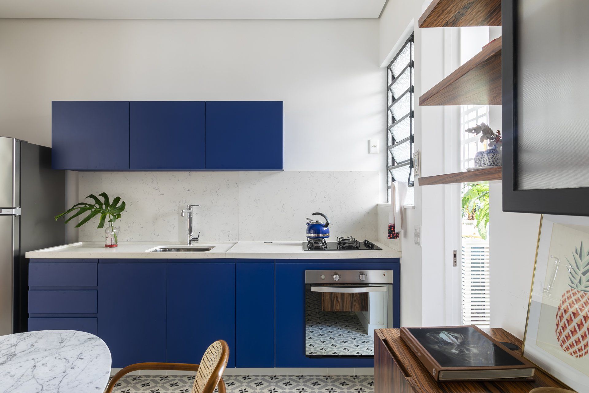 Uma cozinha com armários azuis, fogão, geladeira e mesa.