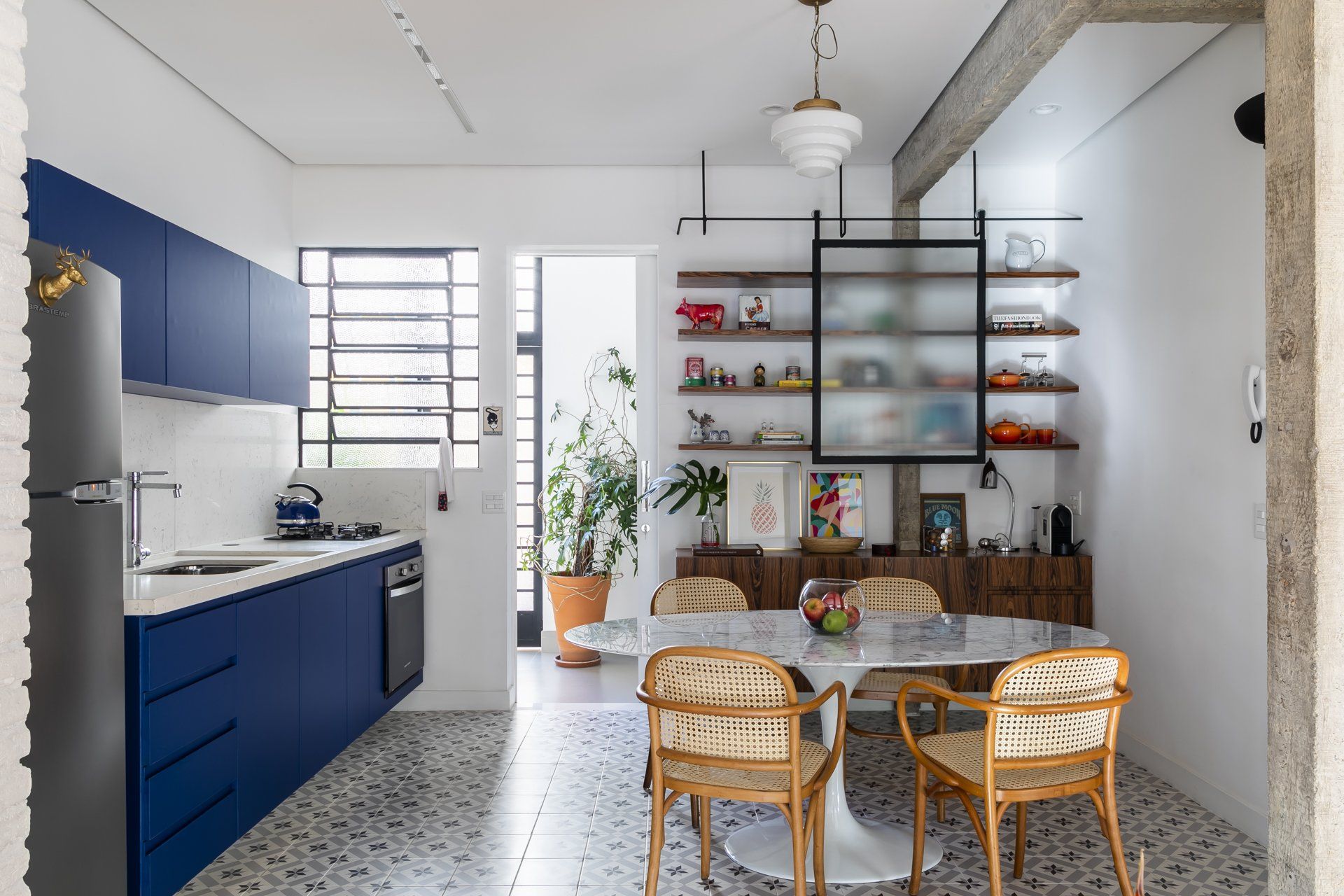 Uma cozinha com armários azuis e uma sala de jantar com mesa e cadeiras.