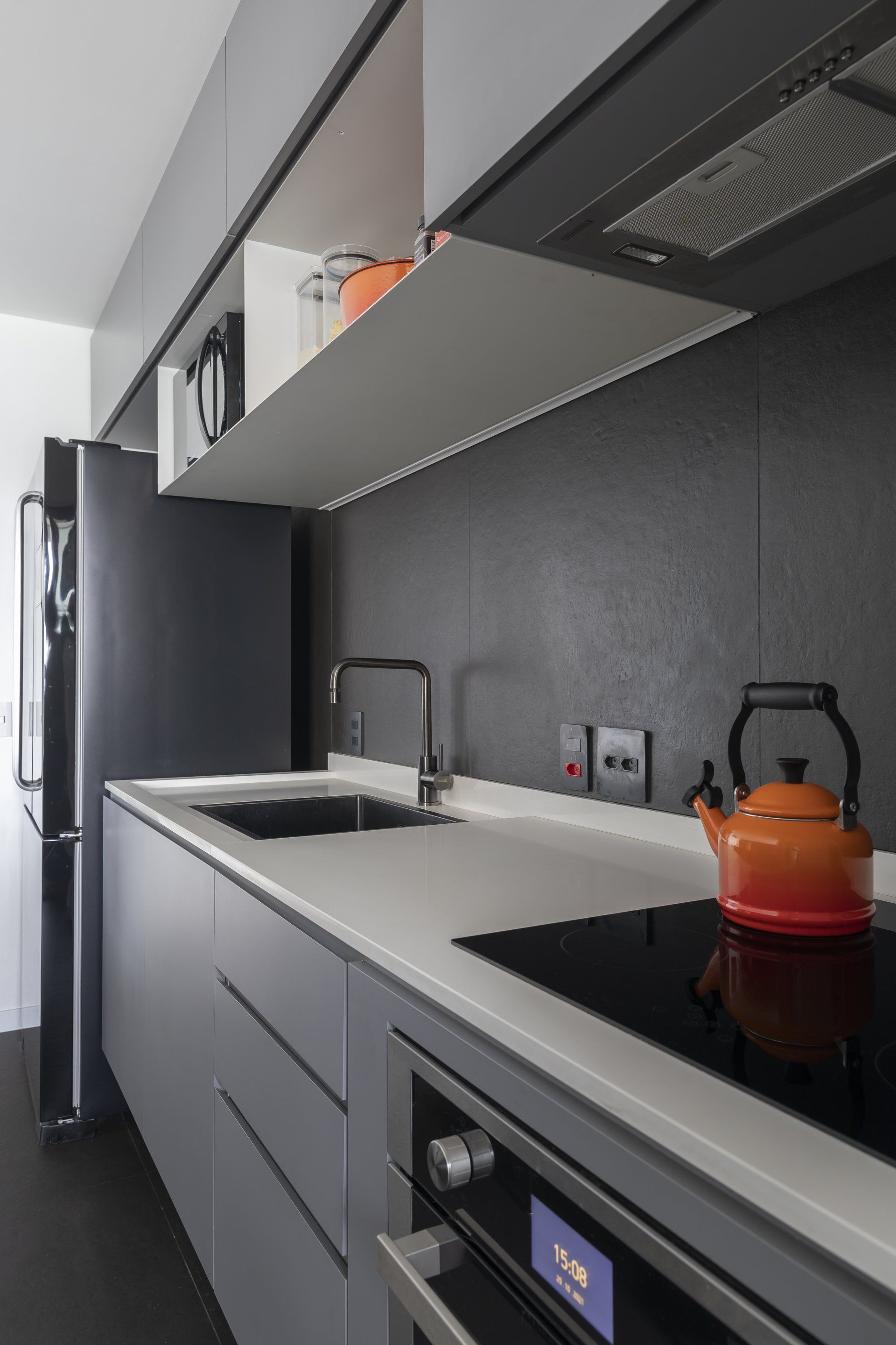 Uma cozinha com fogão, forno, pia e geladeira.