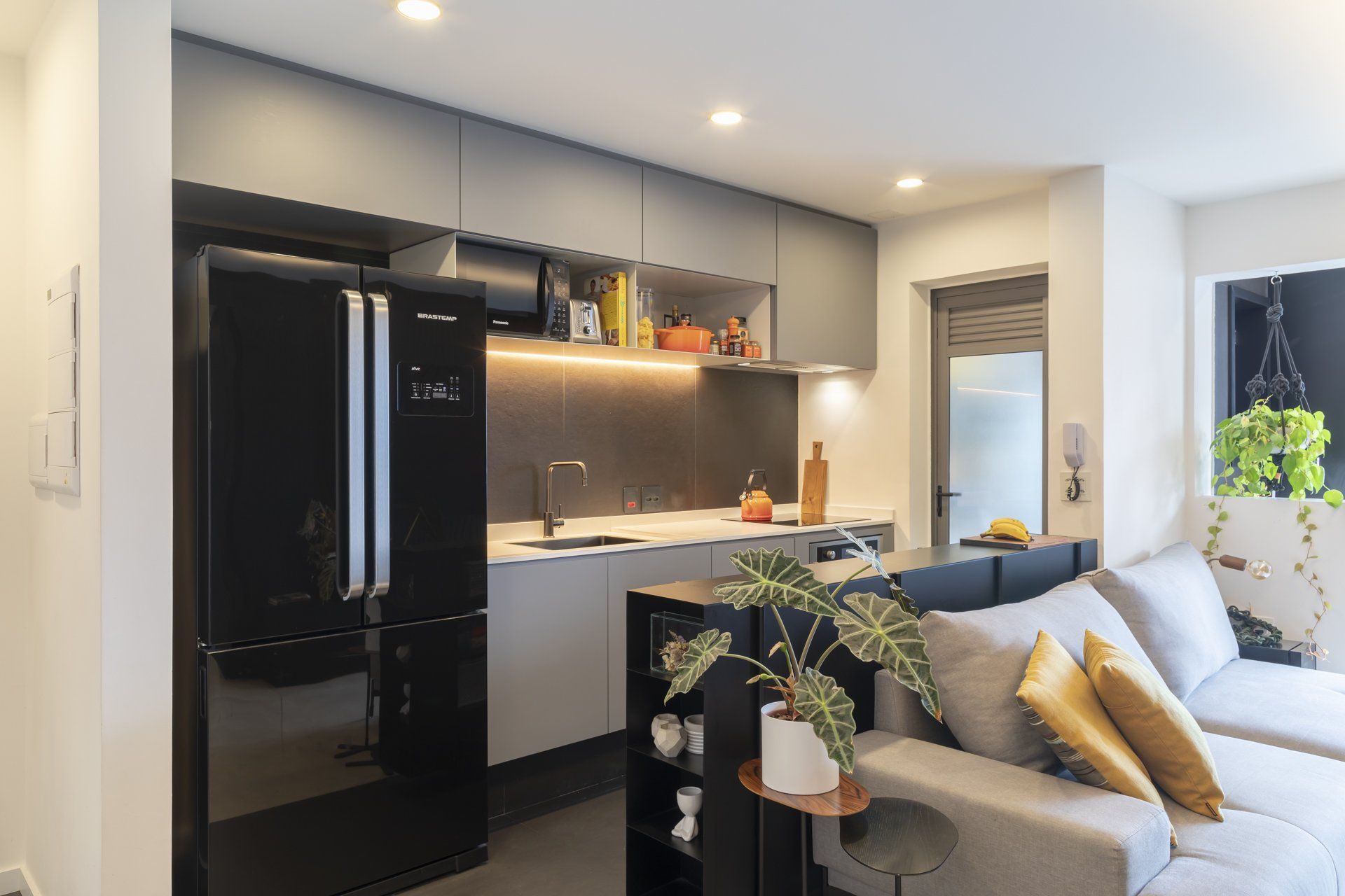 Uma sala de estar com sofá, geladeira e cozinha.