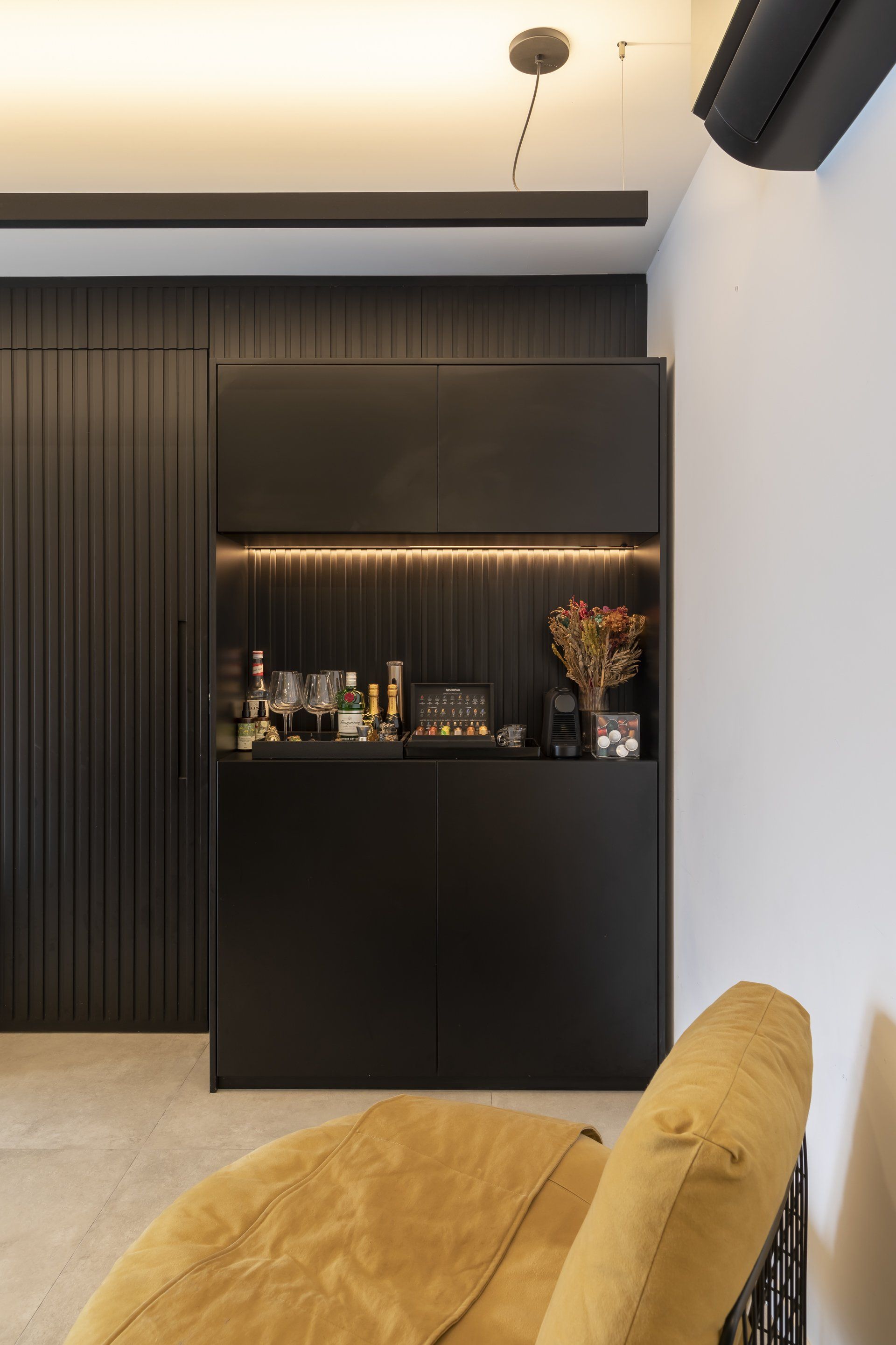 Uma sala com uma cadeira amarela e um bar ao fundo.