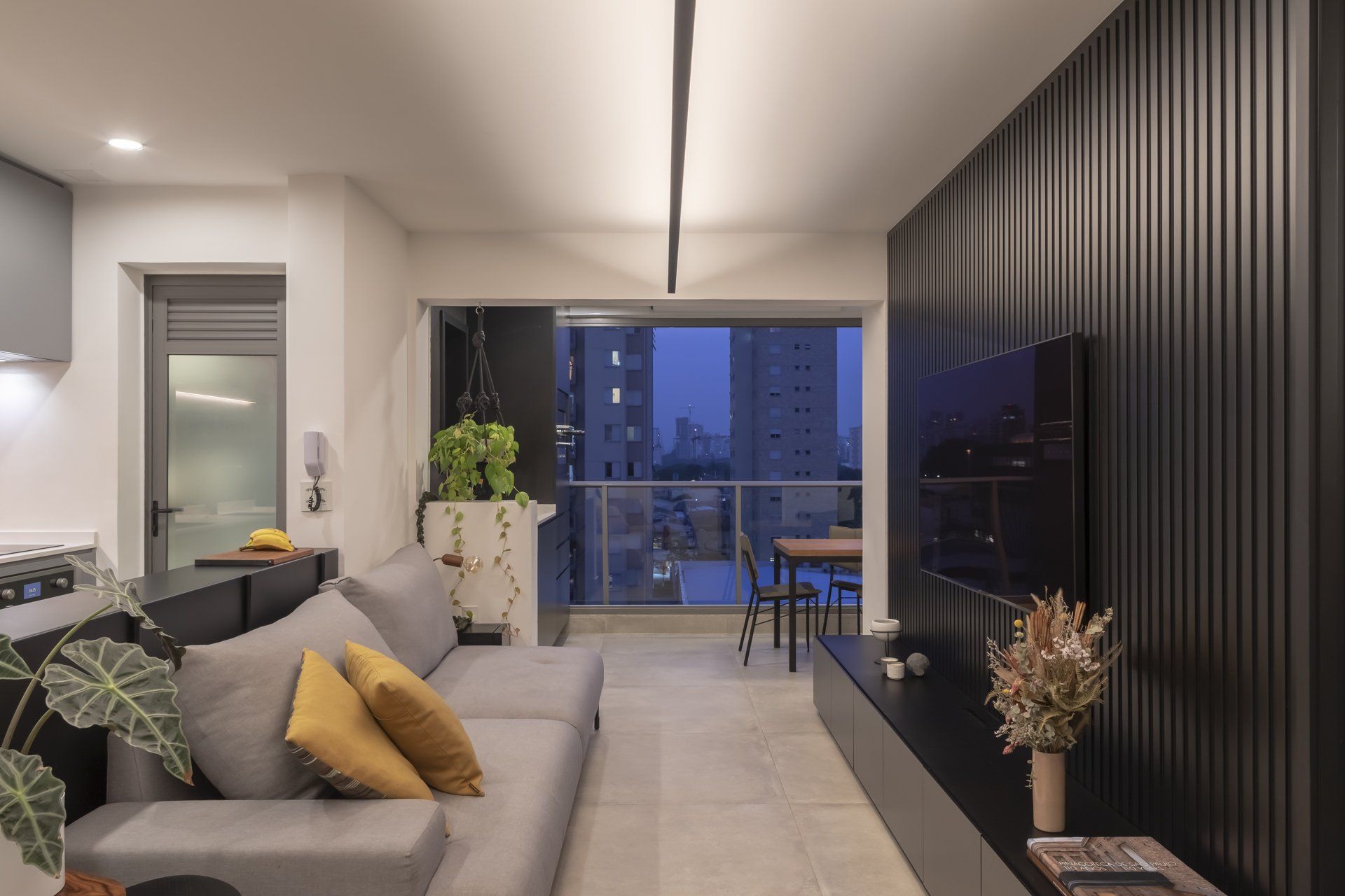 Uma sala de estar com sofá, televisão e varanda.