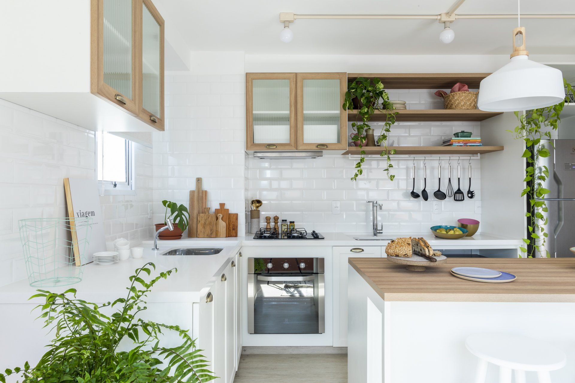 Uma cozinha com armários brancos e bancada de madeira.