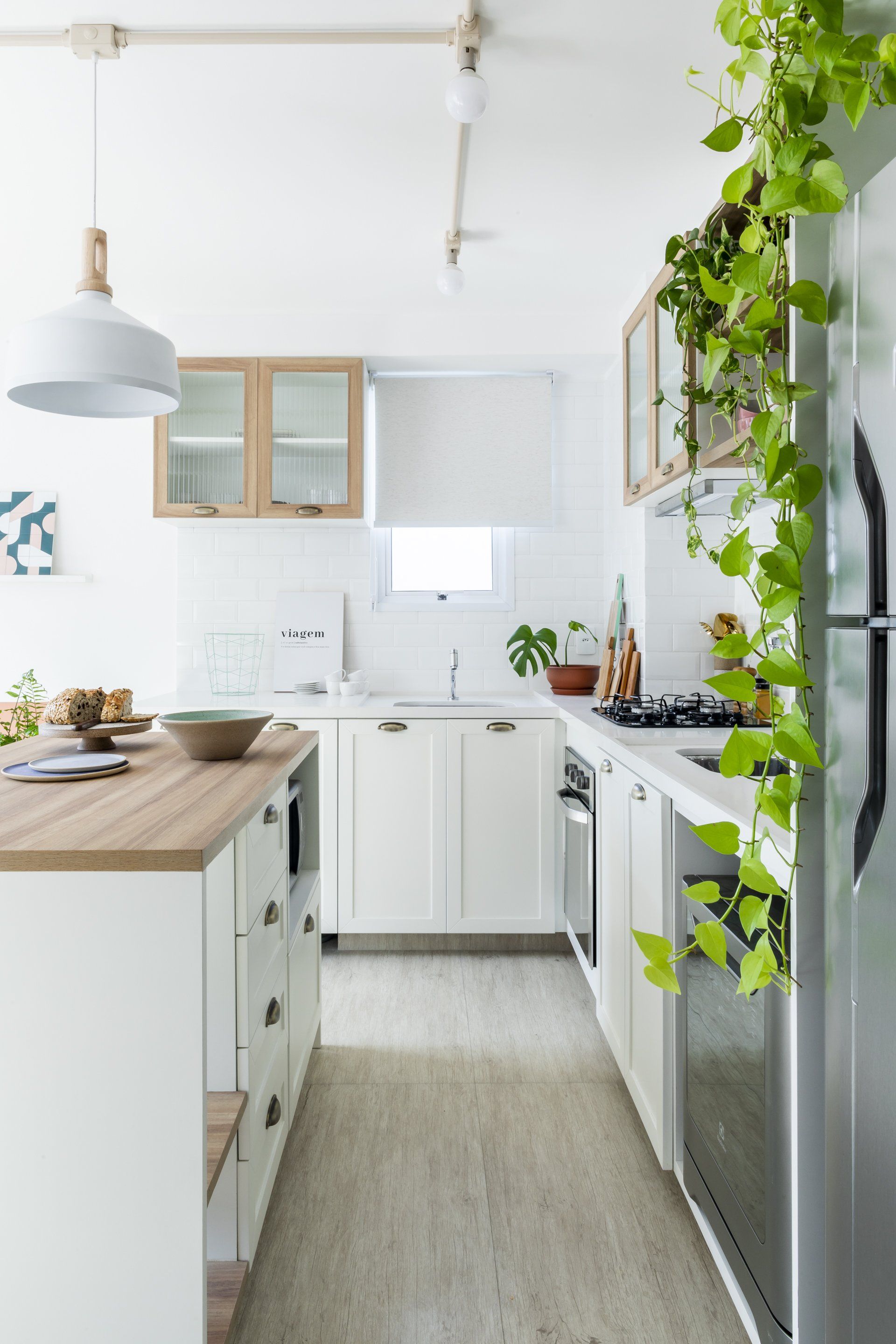Uma cozinha com armários brancos e geladeira de inox.