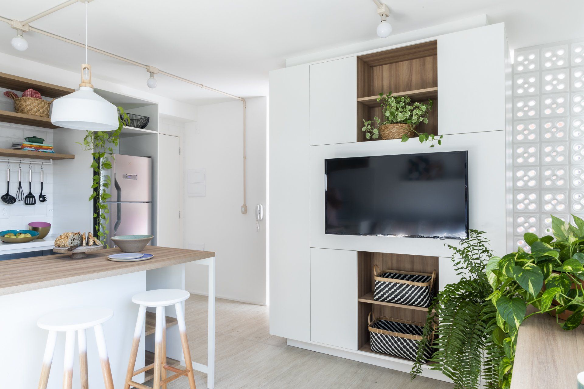 Uma cozinha com armários brancos e uma TV de tela plana na parede.