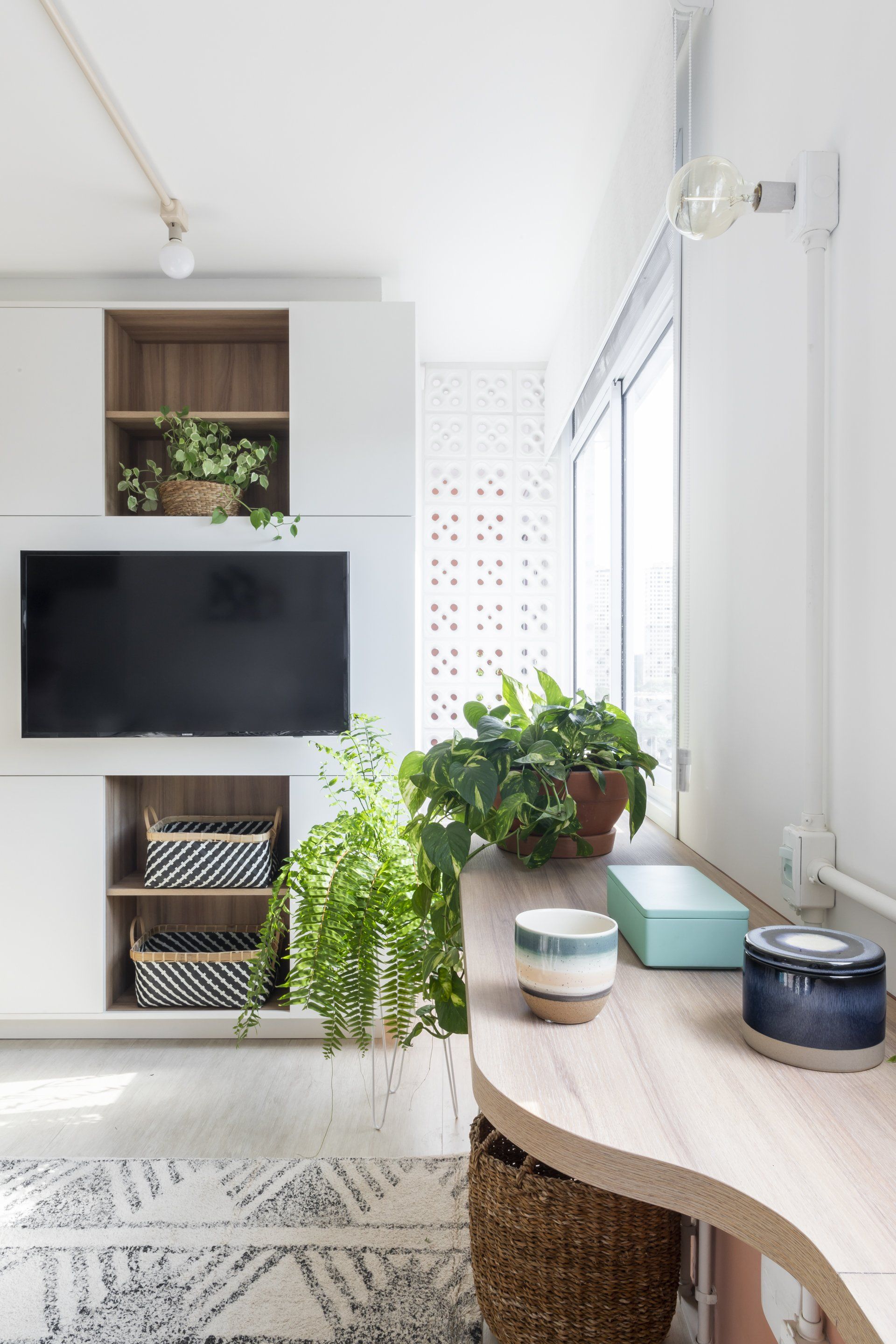 Uma sala de estar com TV de tela plana e uma mesa.