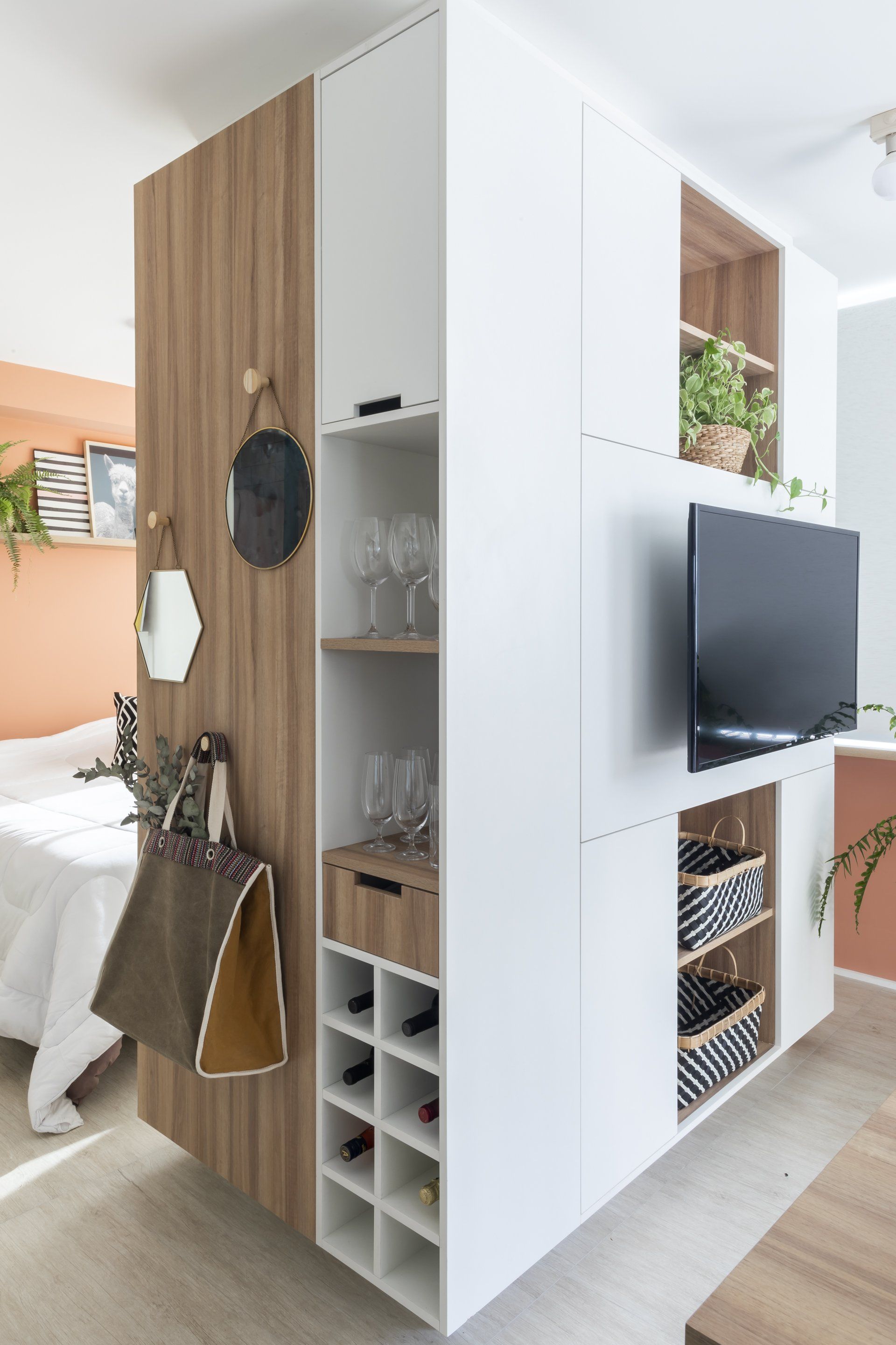 Uma sala com cama, televisão, garrafeira e parede de madeira.