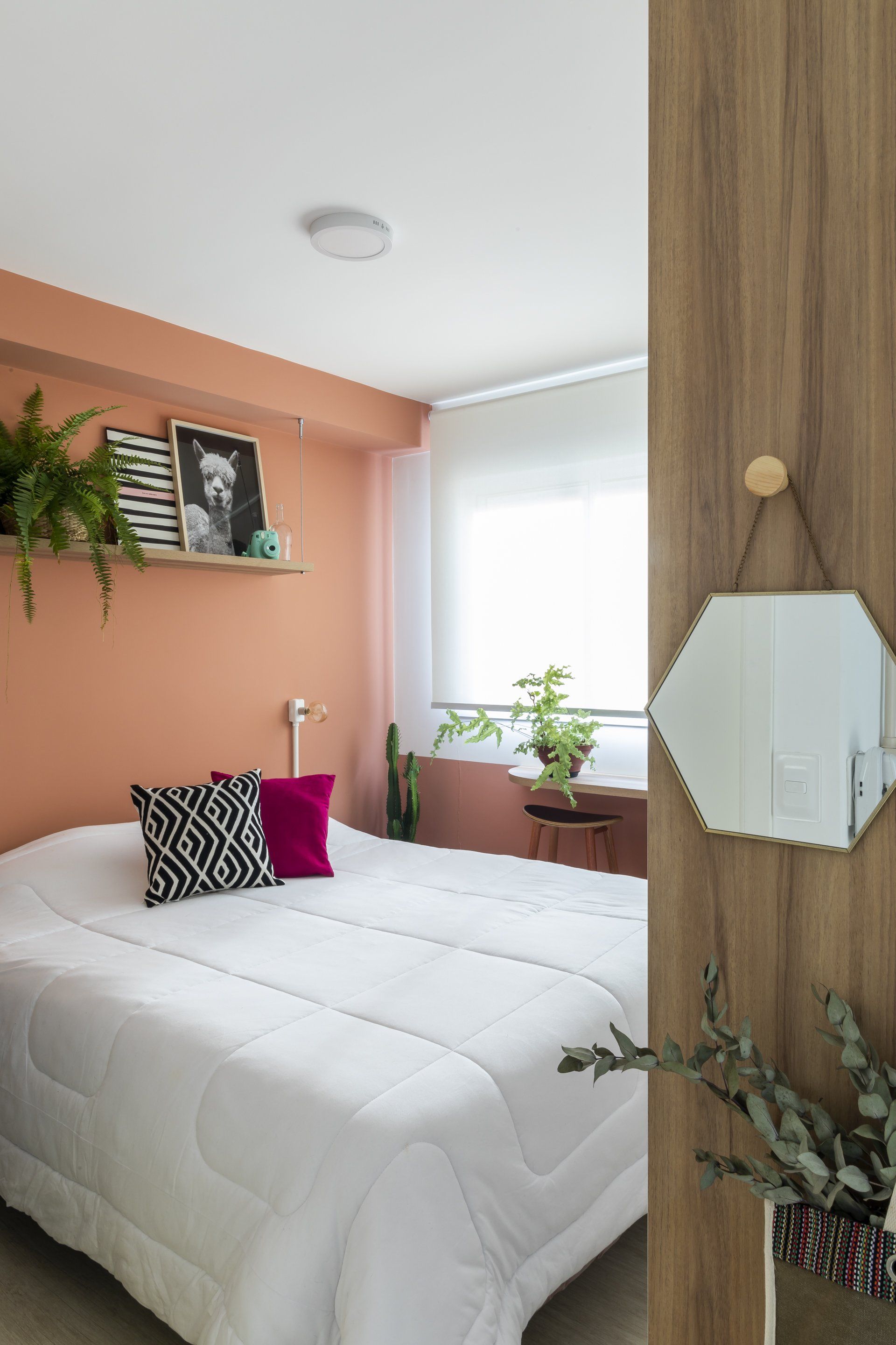 Um quarto com cama e espelho na parede.