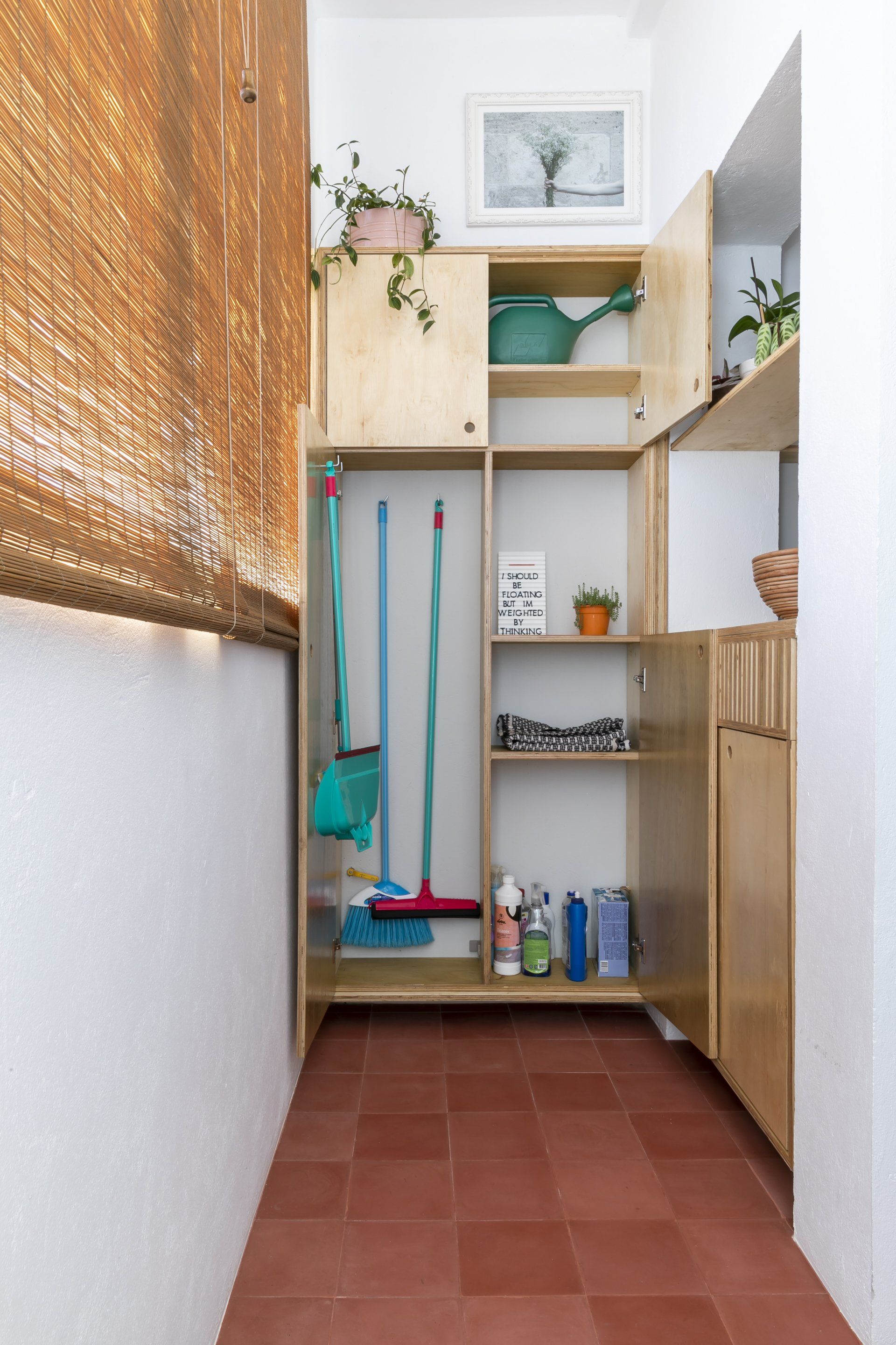 Um corredor estreito com um armário cheio de produtos de limpeza.