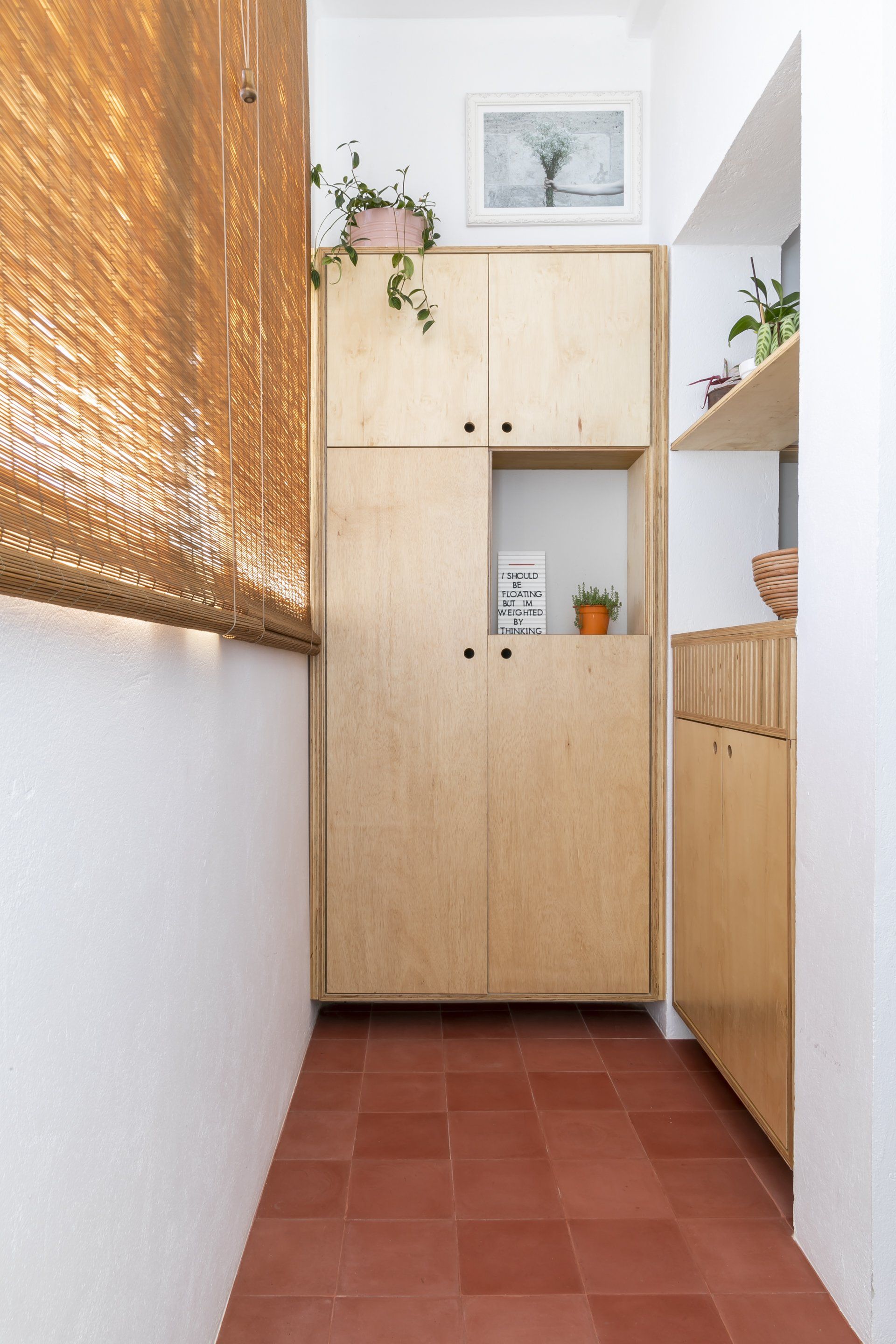 Um corredor com armários de madeira e piso de cerâmica vermelha