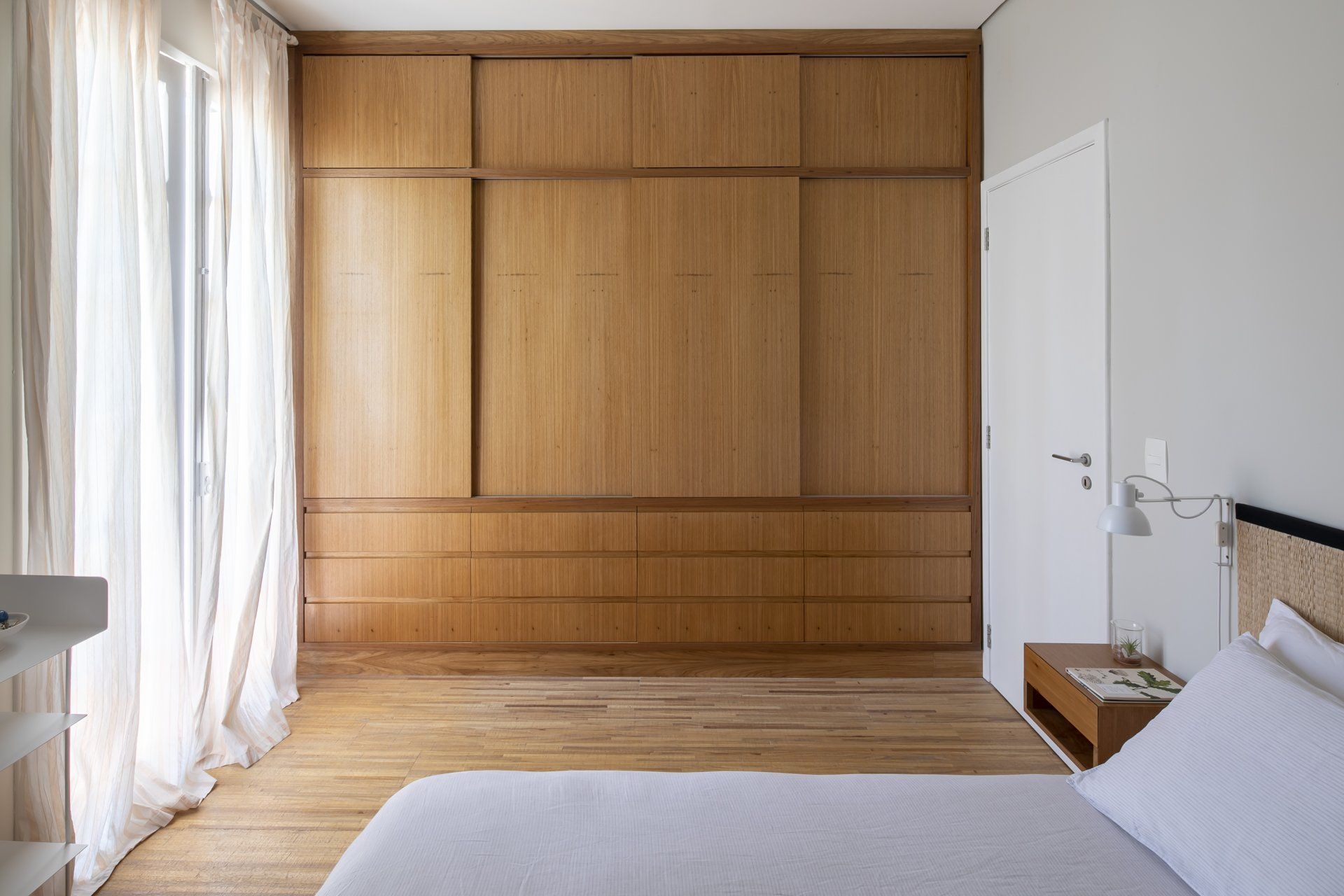 Um quarto com cama, mesa de cabeceira e portas de correr.