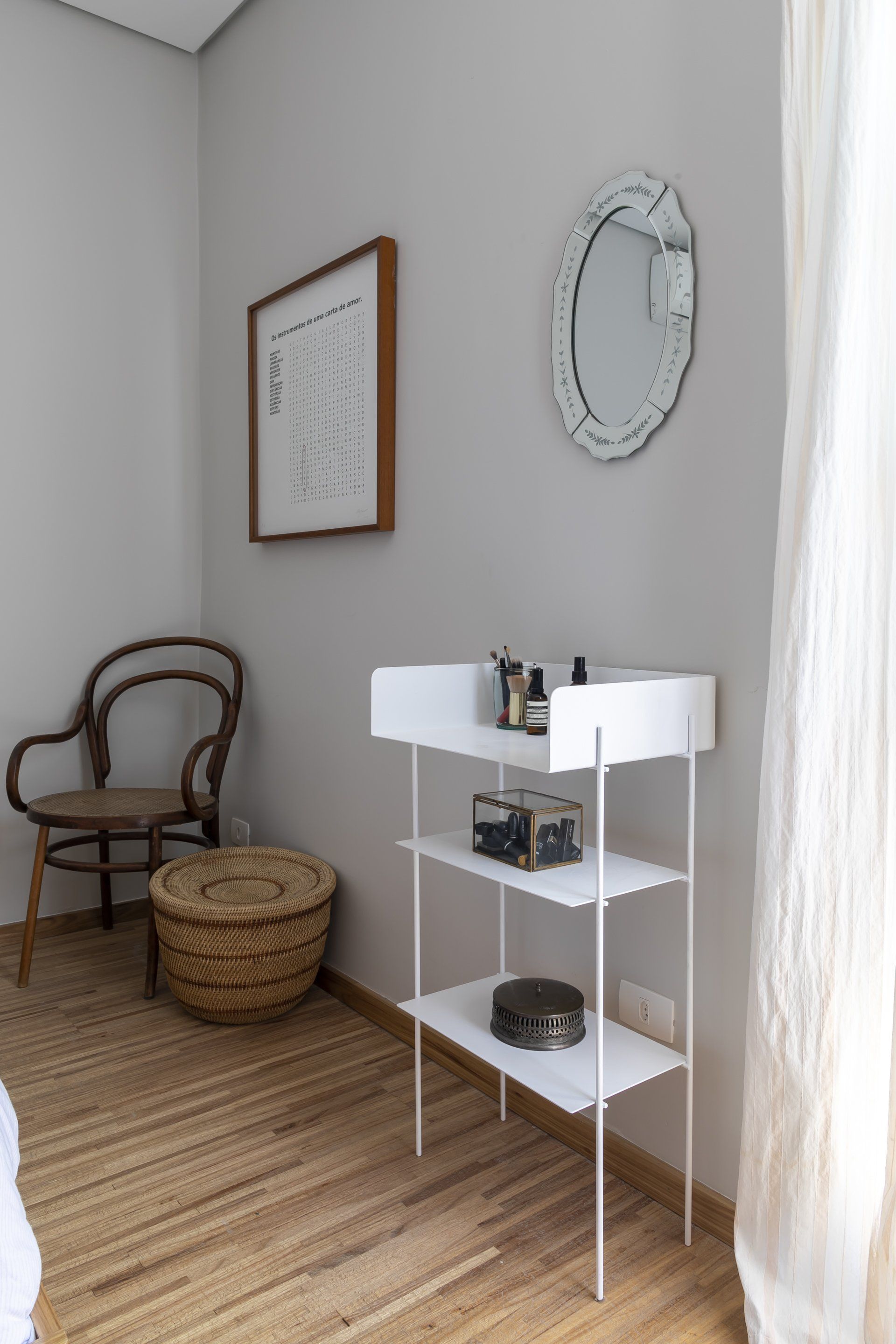 Um quarto com uma prateleira branca, uma cadeira e um espelho.