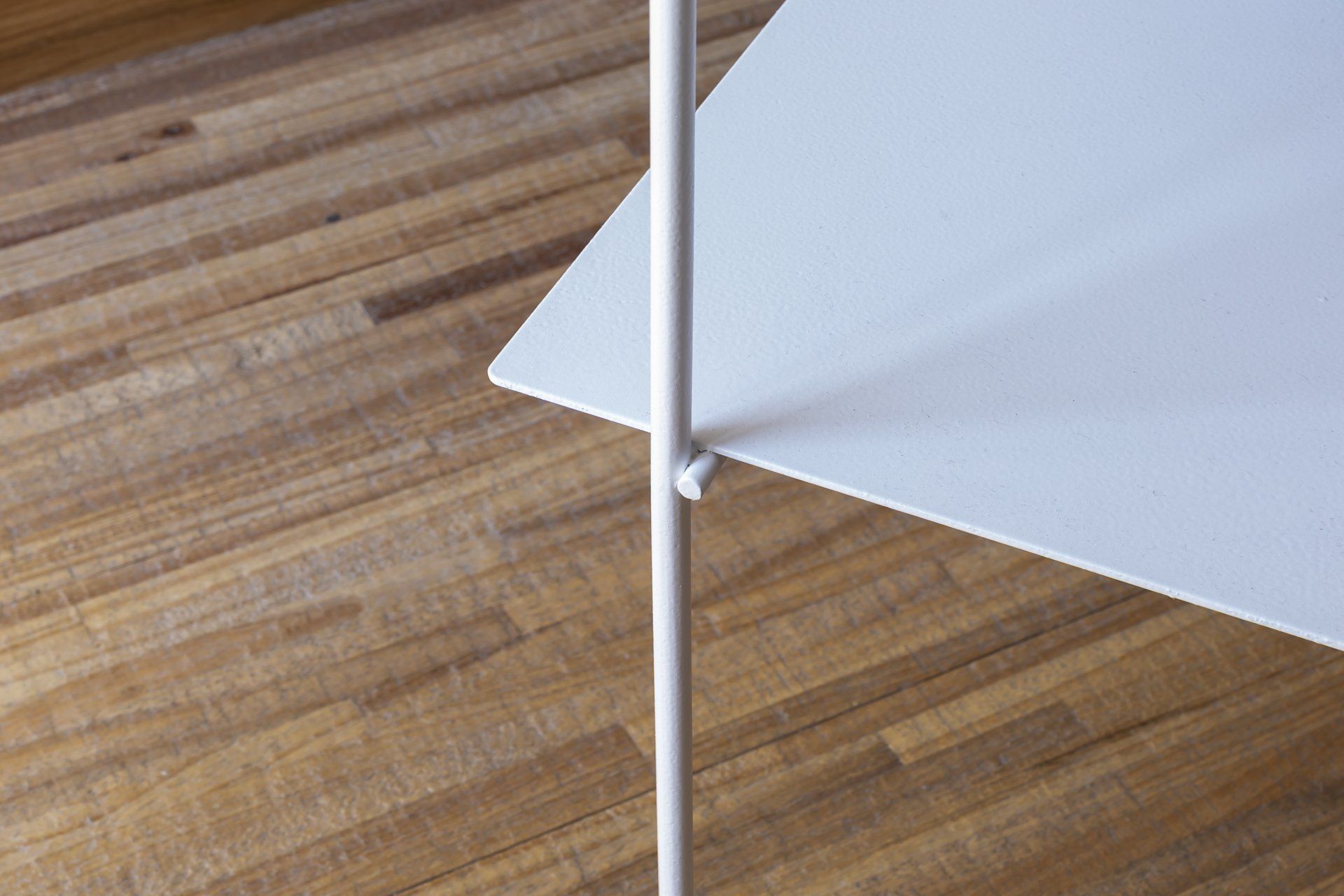 Uma prateleira branca está sobre um chão de madeira.