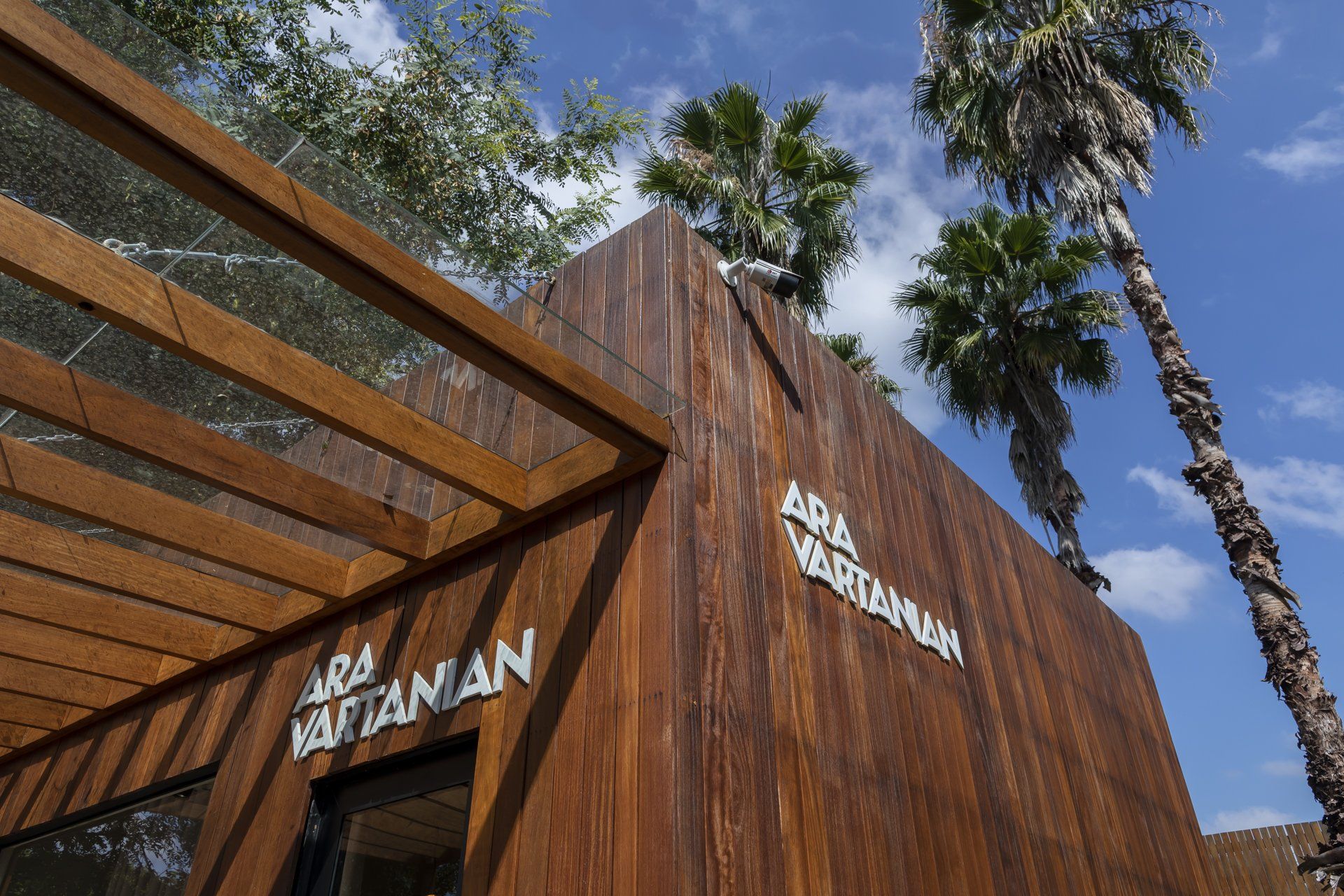 Um prédio de madeira com palmeiras ao fundo.