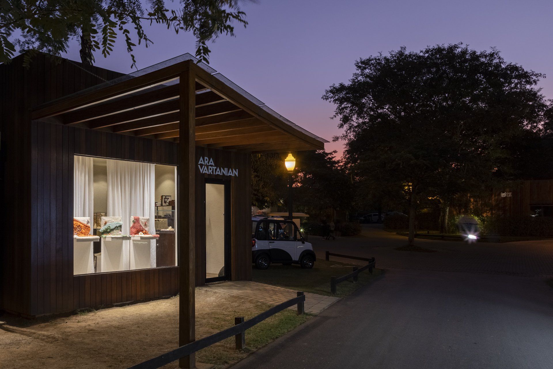 Uma frente de loja com um carro estacionado em frente à noite.