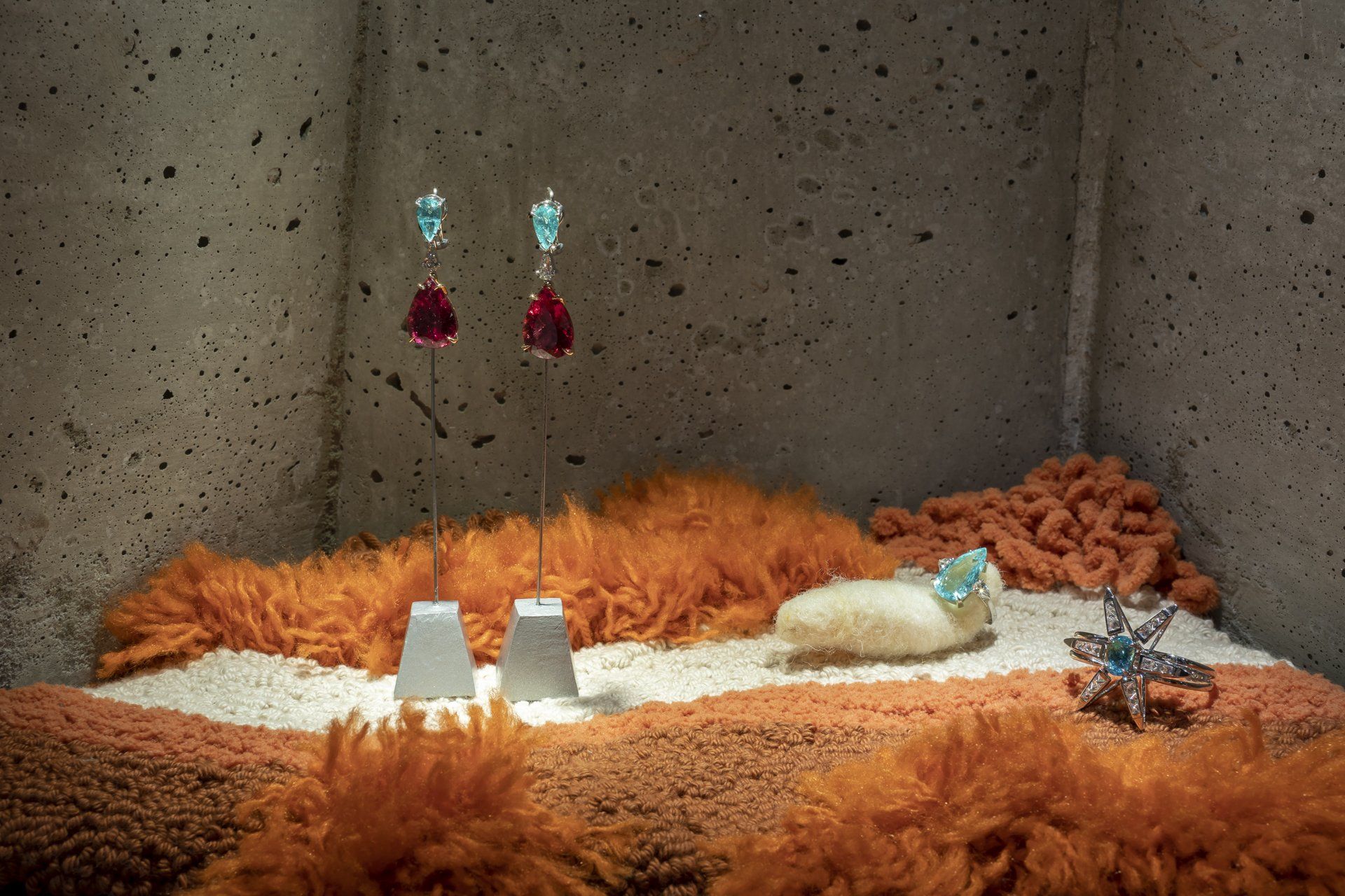 Um gato está deitado em um tapete em uma sala com parede de concreto.