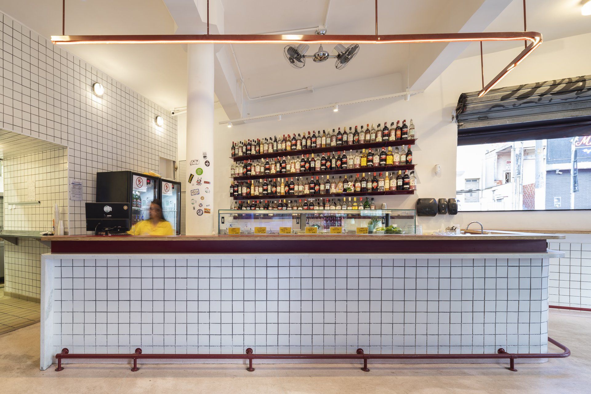 Uma mulher está atrás de um longo balcão branco em um restaurante.