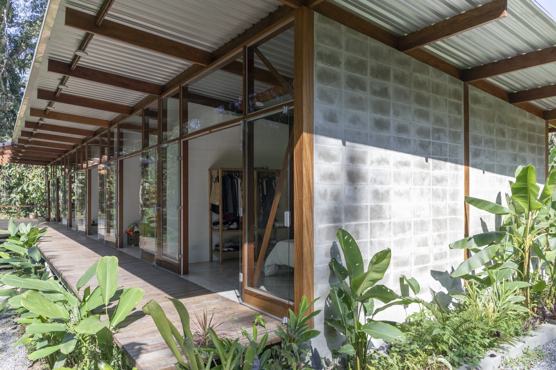 Uma casa com muitas janelas e plantas na frente.