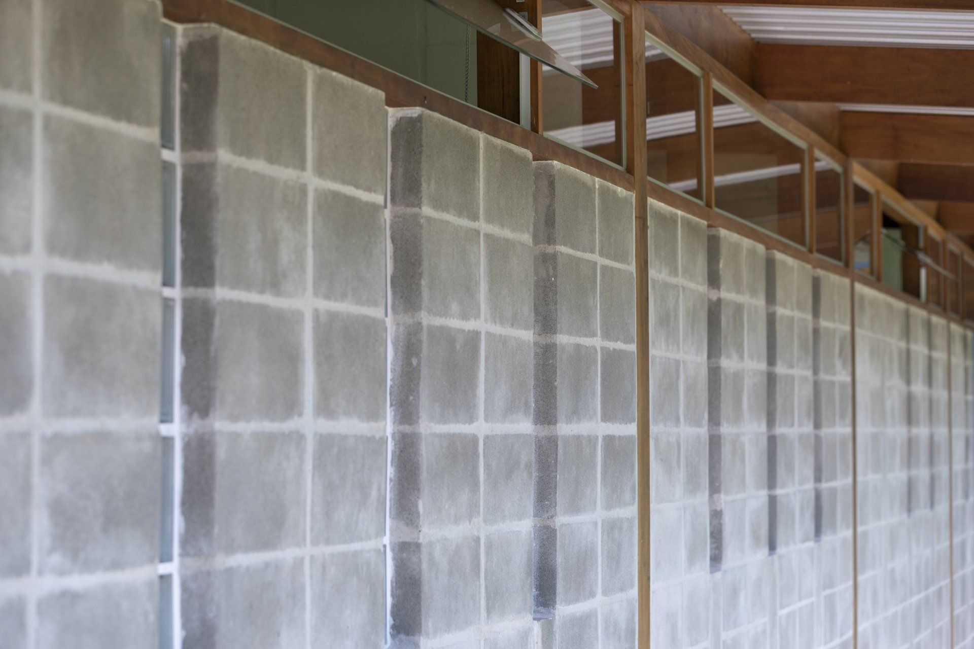 Um longo corredor com parede de tijolos e janelas de madeira.