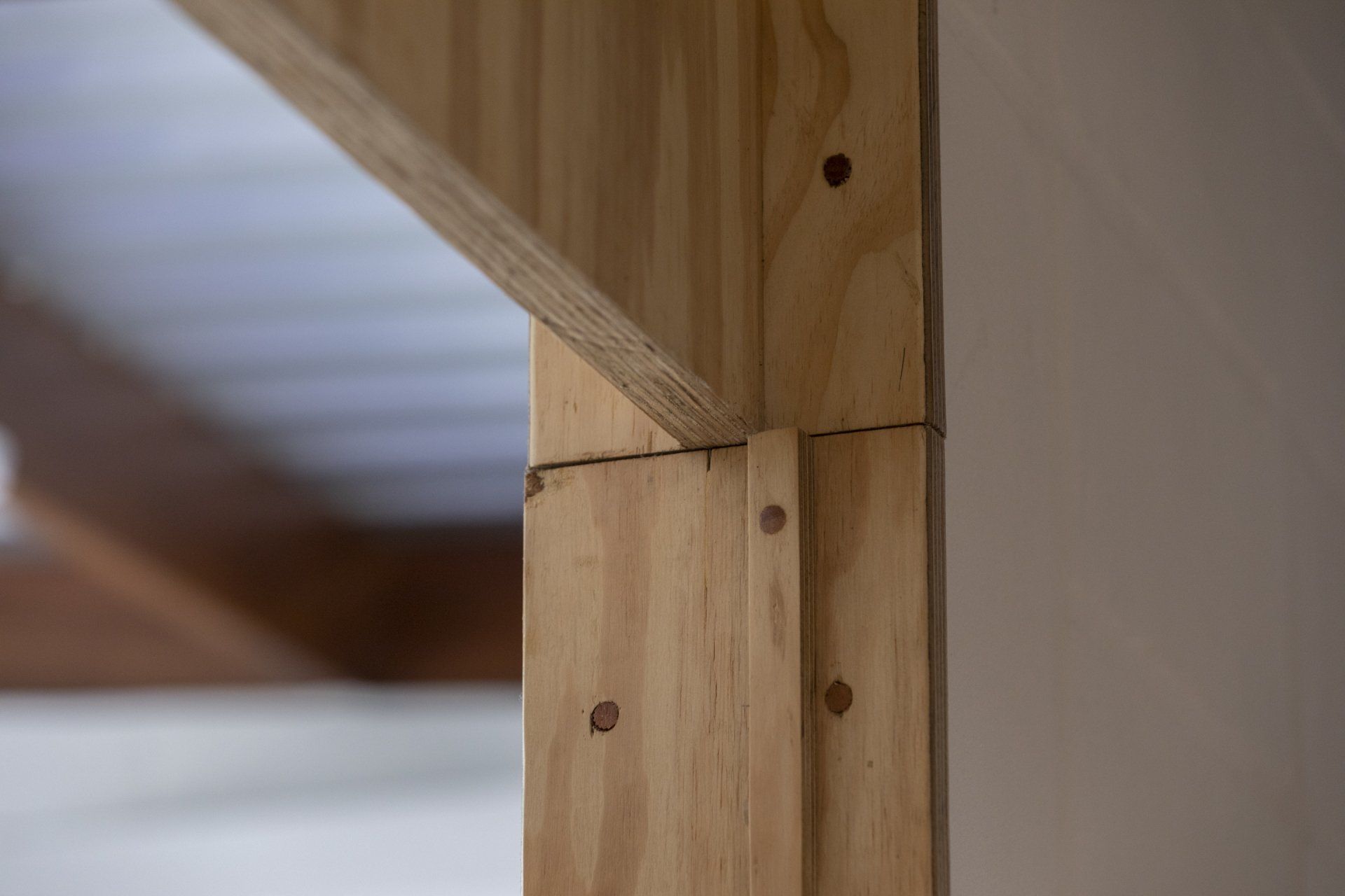 Um close de uma estrutura de madeira com uma cama ao fundo.