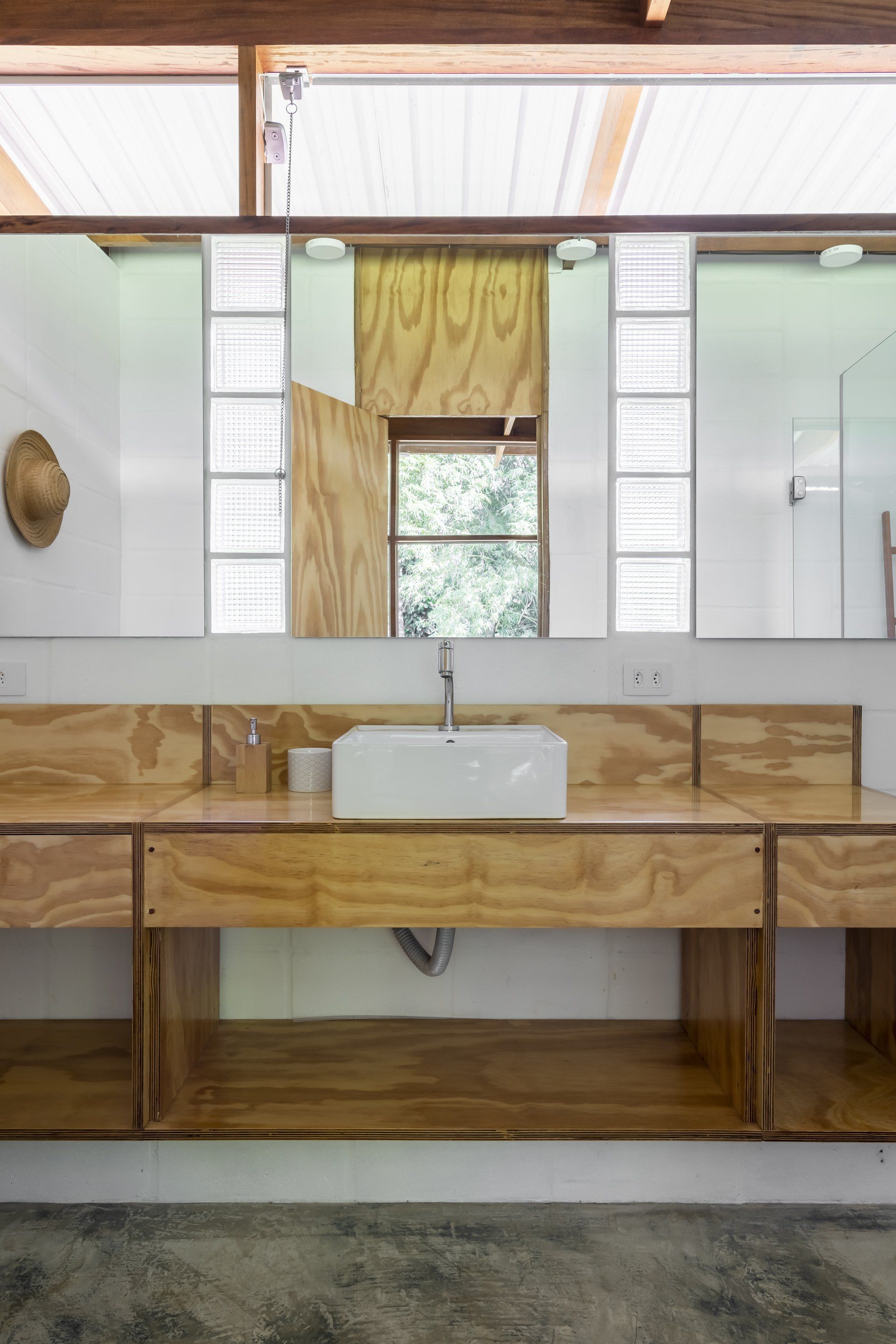 Um banheiro com pia, espelho e armários de madeira.