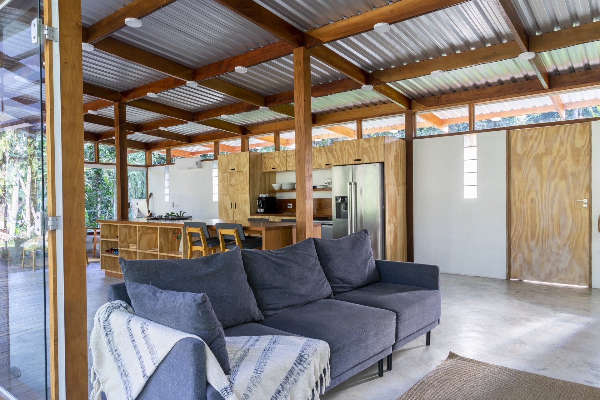 Uma sala com um sofá e uma cadeira e uma cozinha ao fundo.