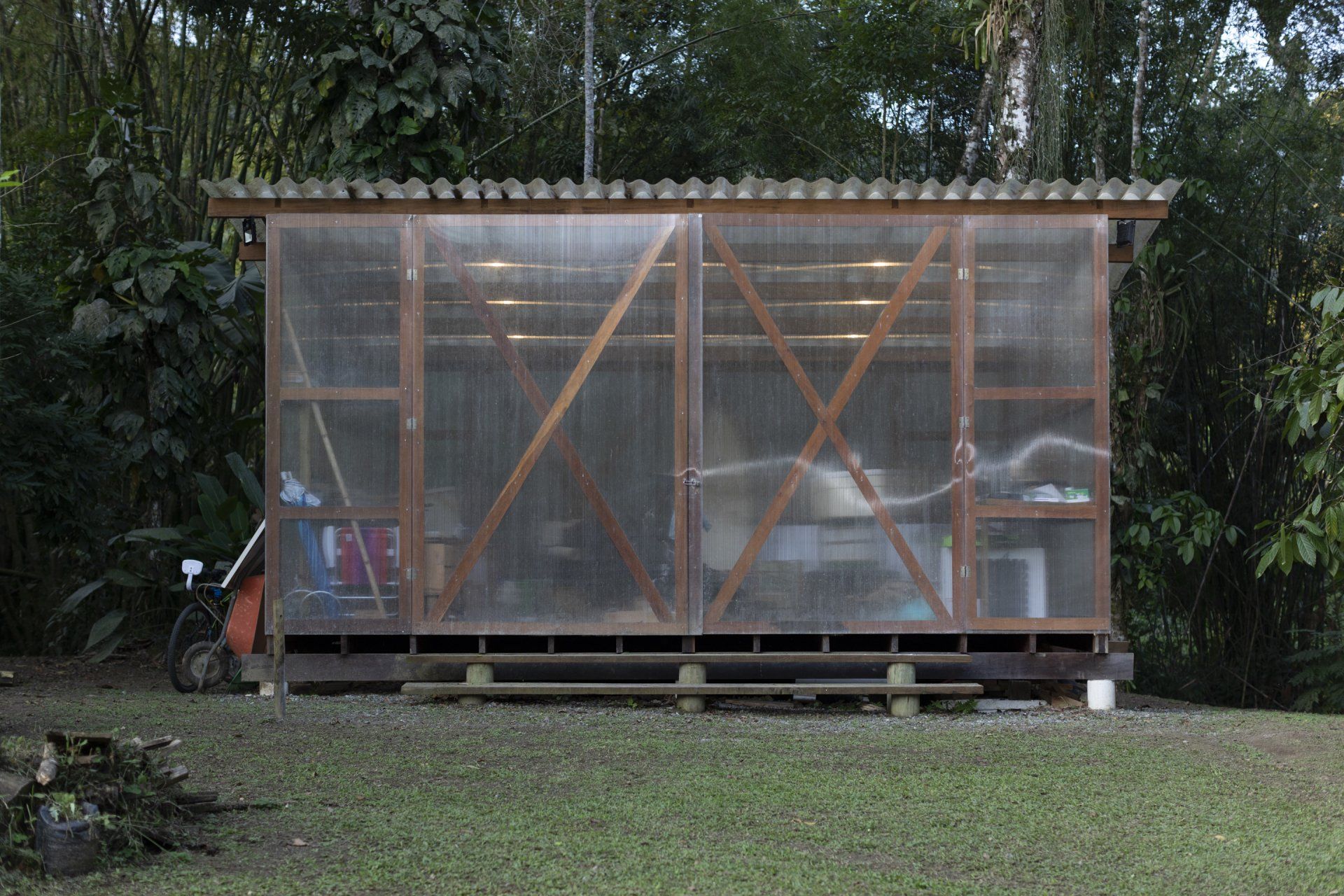 Um galpão de madeira com telhado de plástico transparente está no meio de um campo gramado.