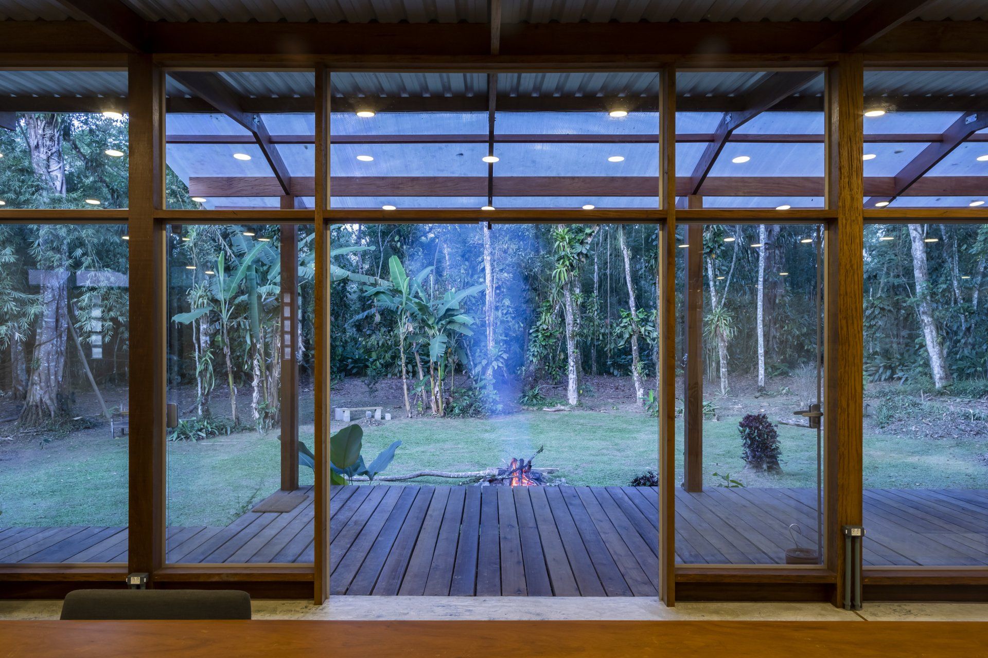 Uma grande janela com vista para um deck de madeira e árvores.