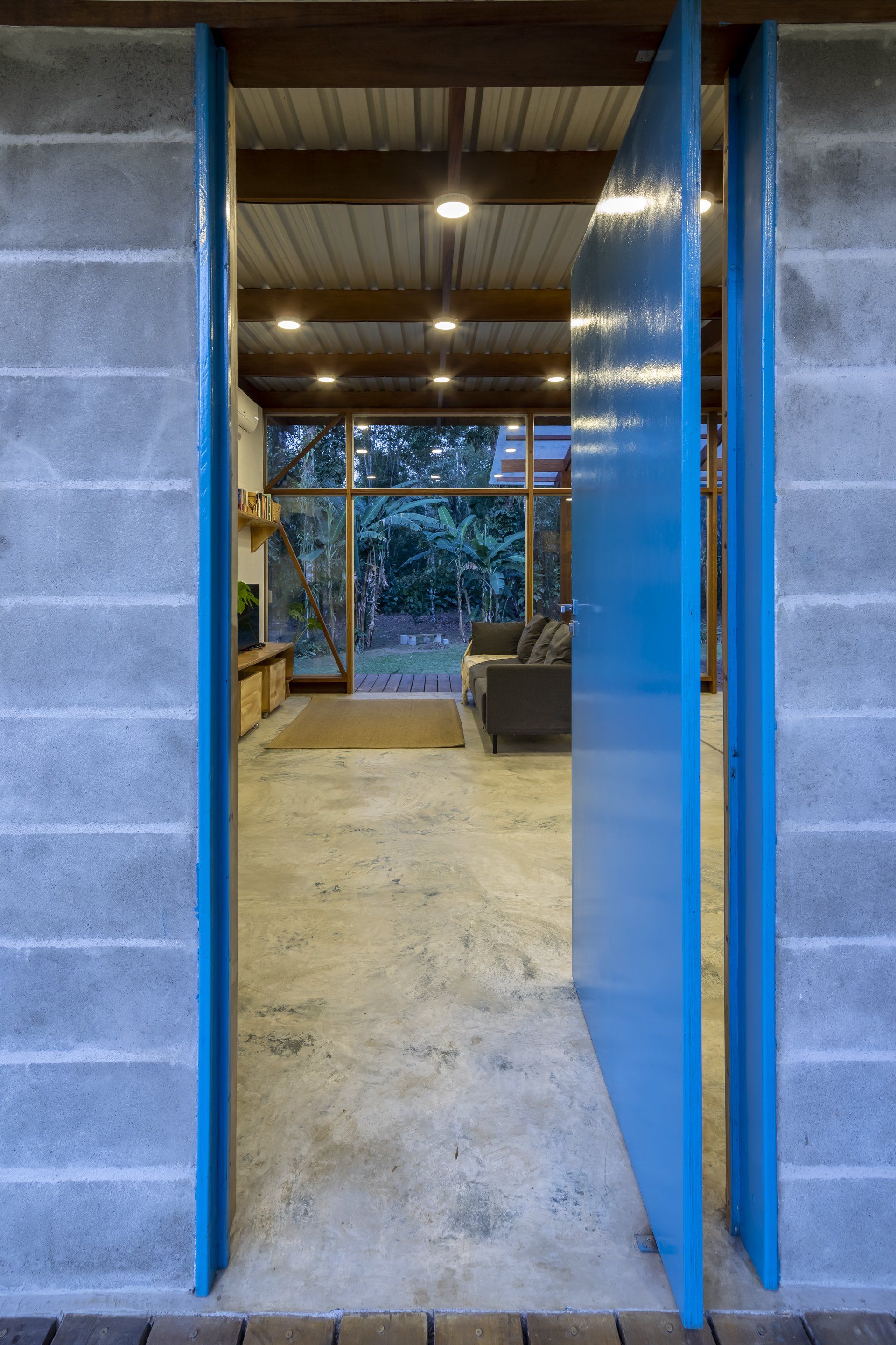 Uma porta azul está aberta para uma sala de estar em uma casa.