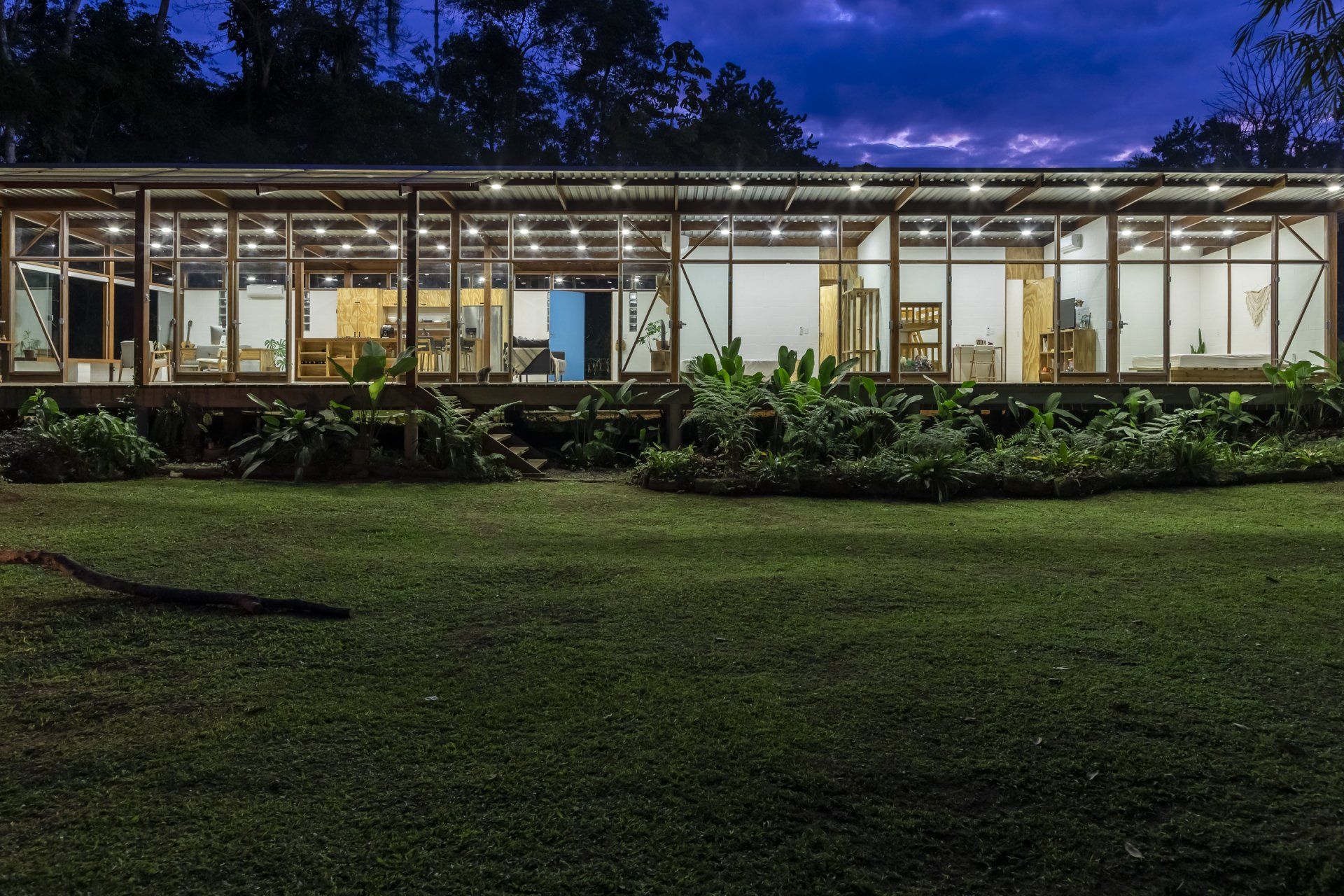 Uma casa grande com muitas janelas fica iluminada à noite
