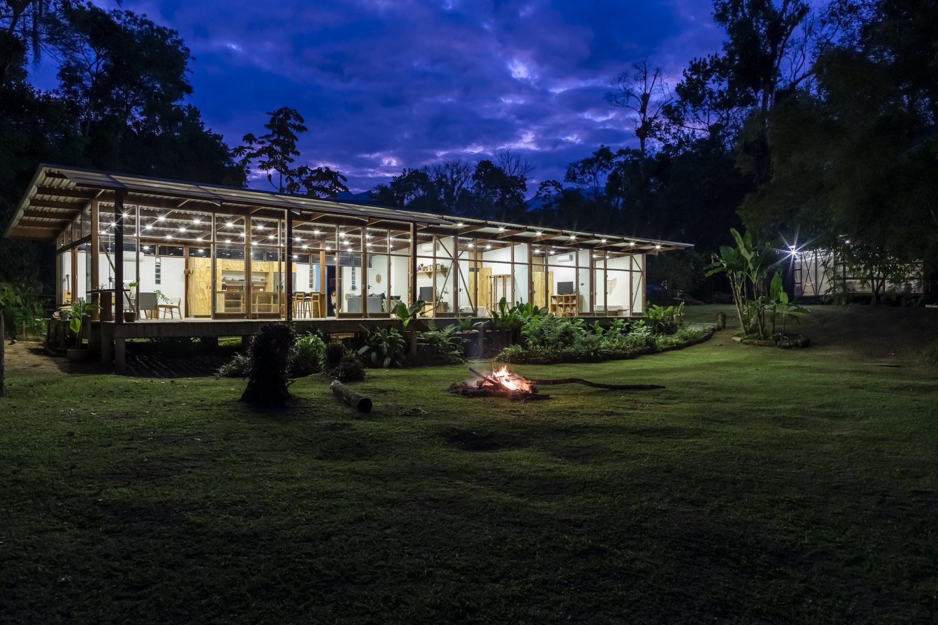 Uma casa grande com uma fogueira na frente à noite.