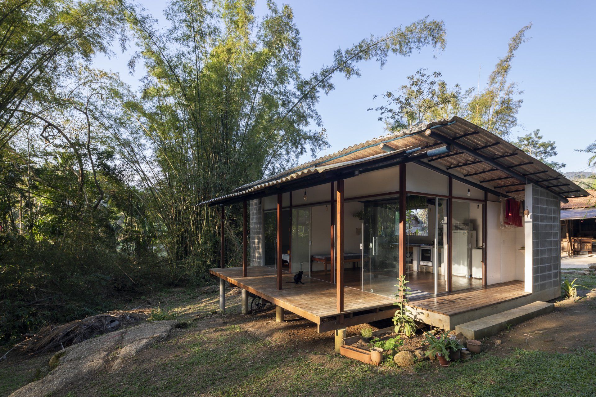 Uma pequena casa com muitas janelas é cercada por árvores.