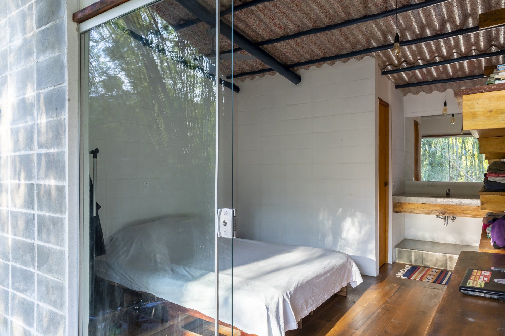 Um quarto com cama atrás de uma parede de vidro.