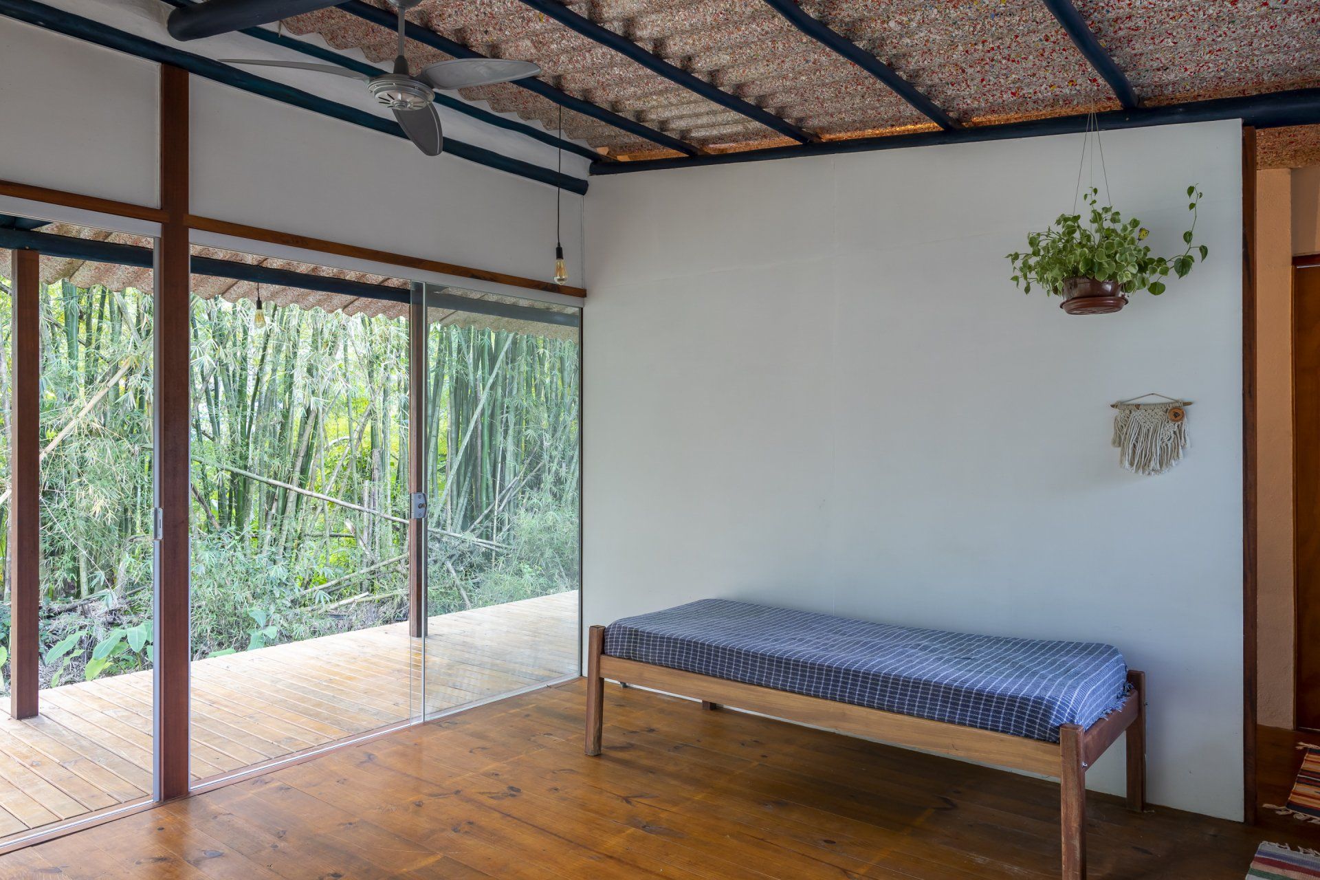 Tem uma cama no meio do quarto com ventilador de teto.