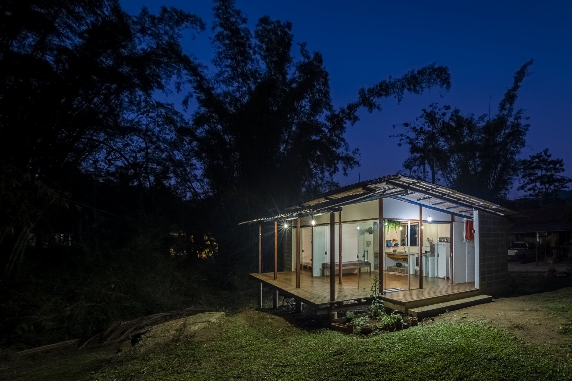 Uma pequena casa é iluminada à noite no meio de uma floresta.