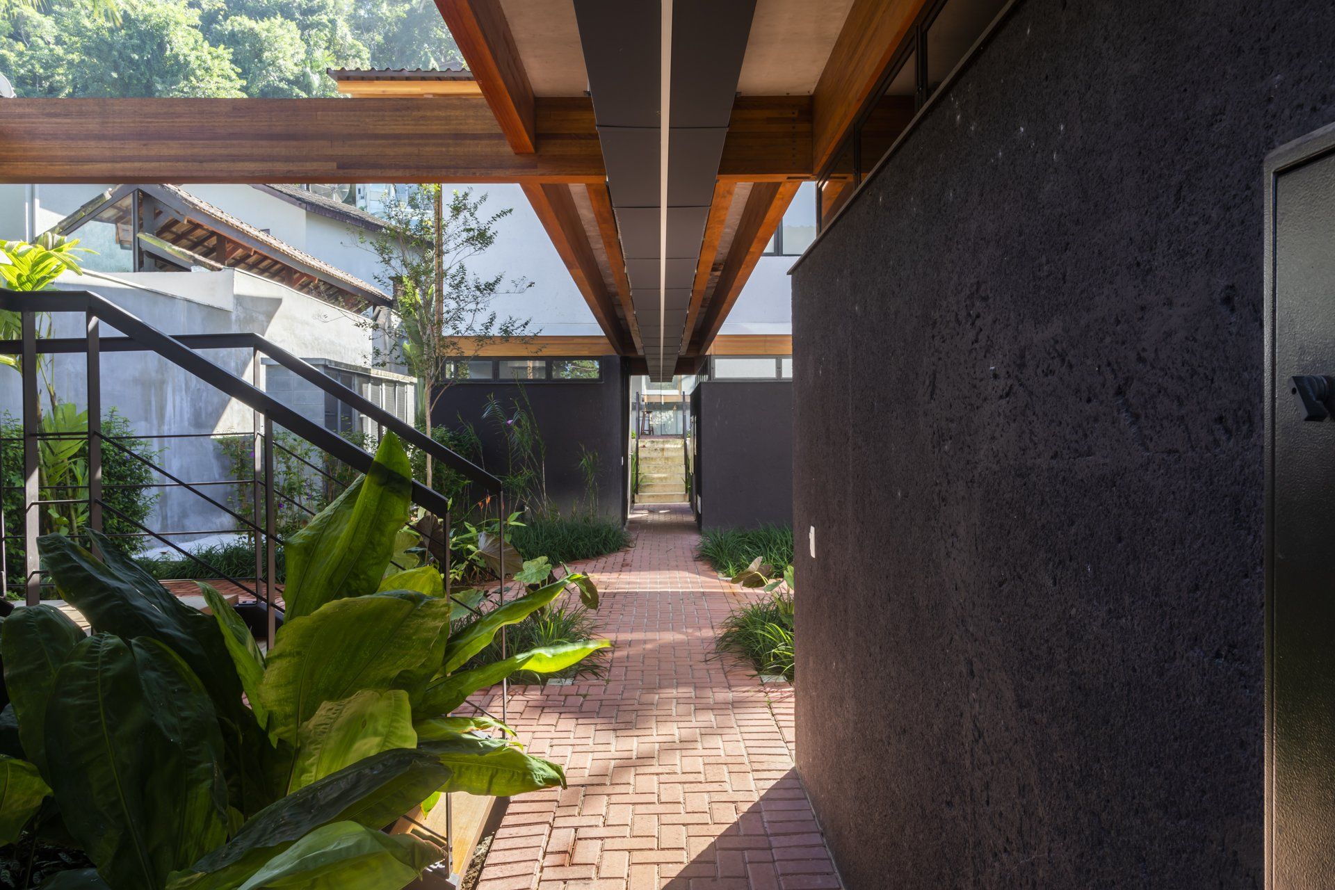 Uma passarela de tijolos entre dois edifícios com teto de madeira.