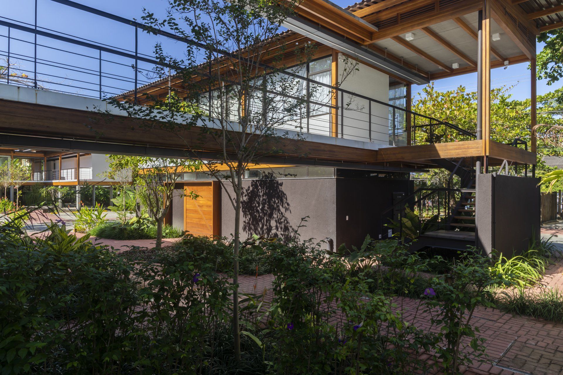 Uma casa com deck de madeira é cercada por árvores e arbustos.
